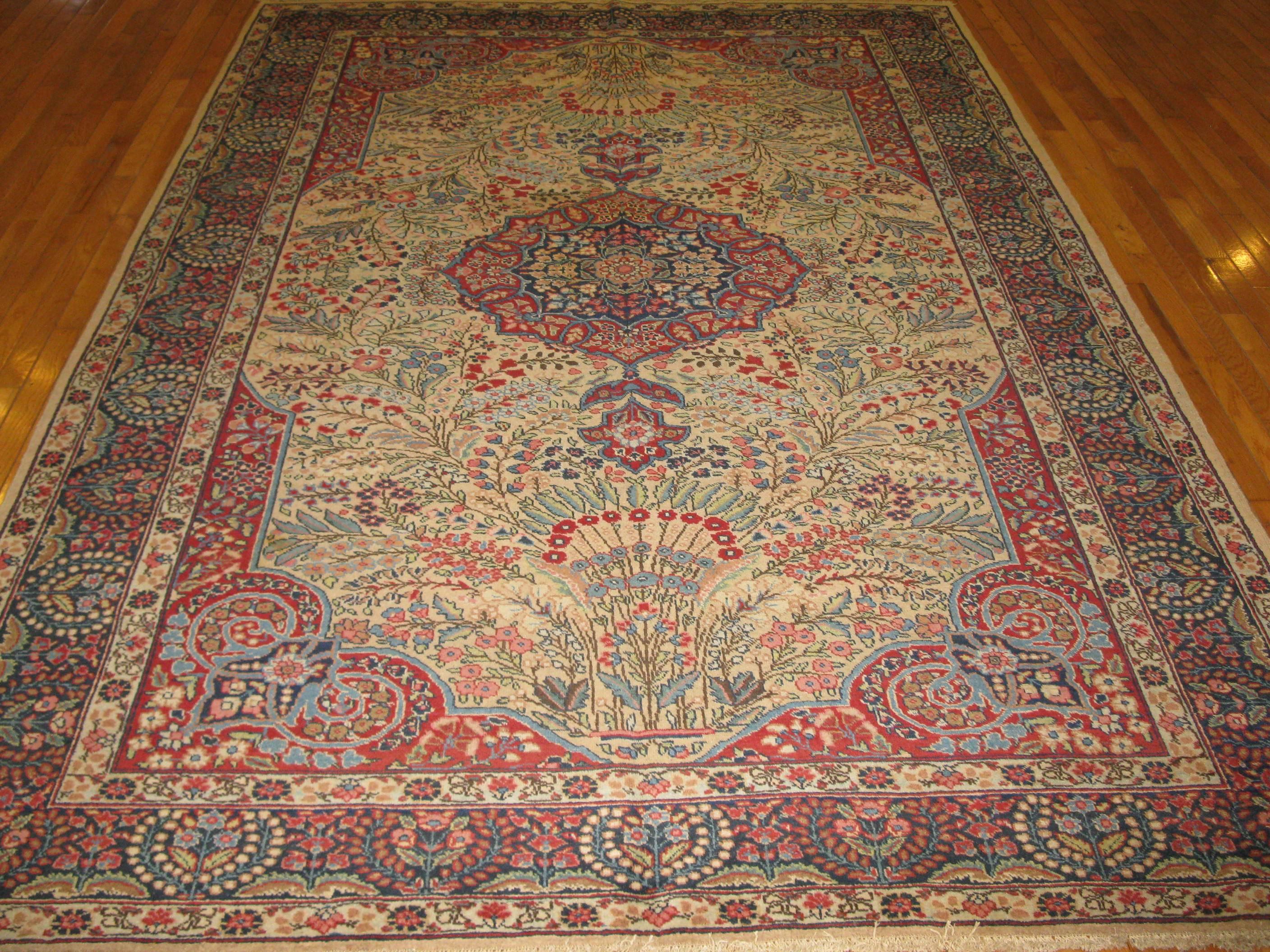 This is a beautiful antique hand-knotted Persian Kerman rug with an elegant traditional central and corner medallion design. It is made with wool pile colored with natural dyes on a cotton foundation. The rug measures 6'6" x 10'.