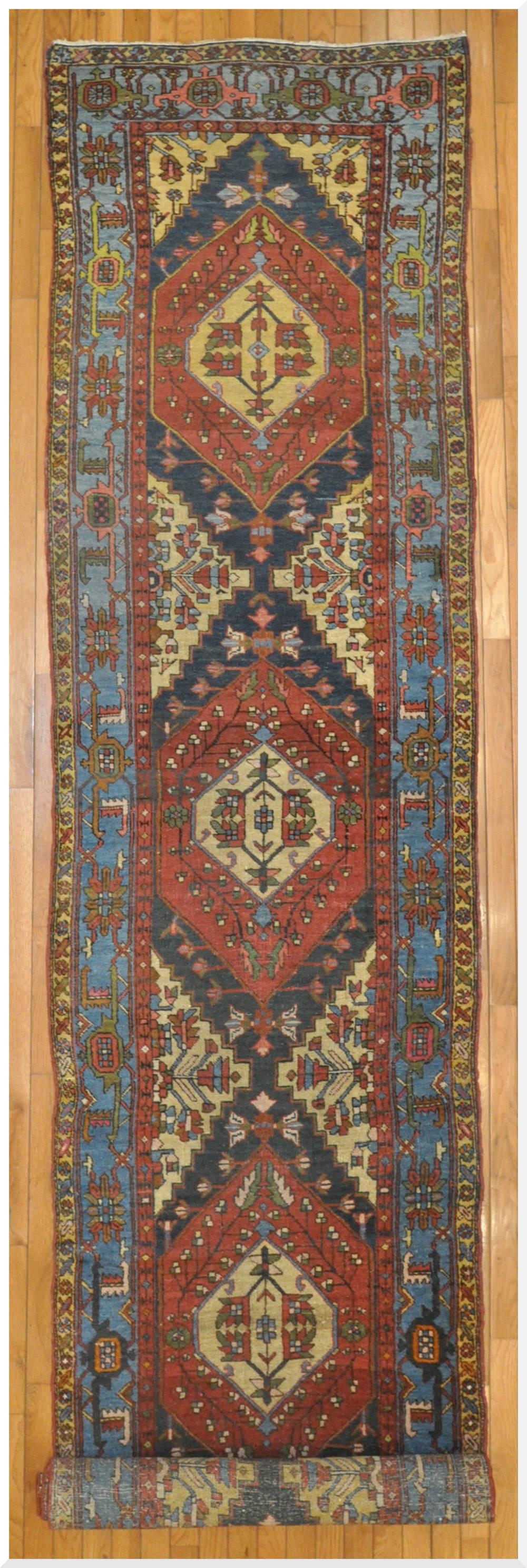 This is a beautiful antique hand-knotted Persian Heriz runner rug with multiple geometric medallion design on a red color field. The rug has a very fine weave and in excellent condition. It measures 2'10'' x 14' 4''.