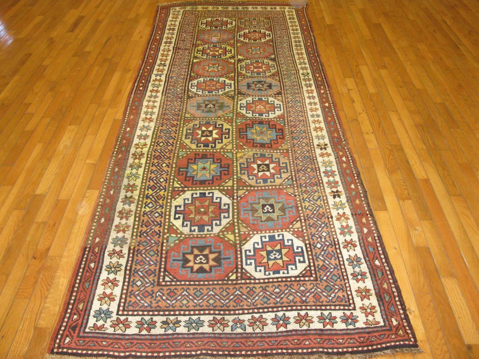 This is a beautiful antique hand-knotted Caucasian Kazak rug made with all wool and natural dyes. The rug has a traditional repetitive medallions geometric design. It is in great condition and measures about 3'9'' x 11'.