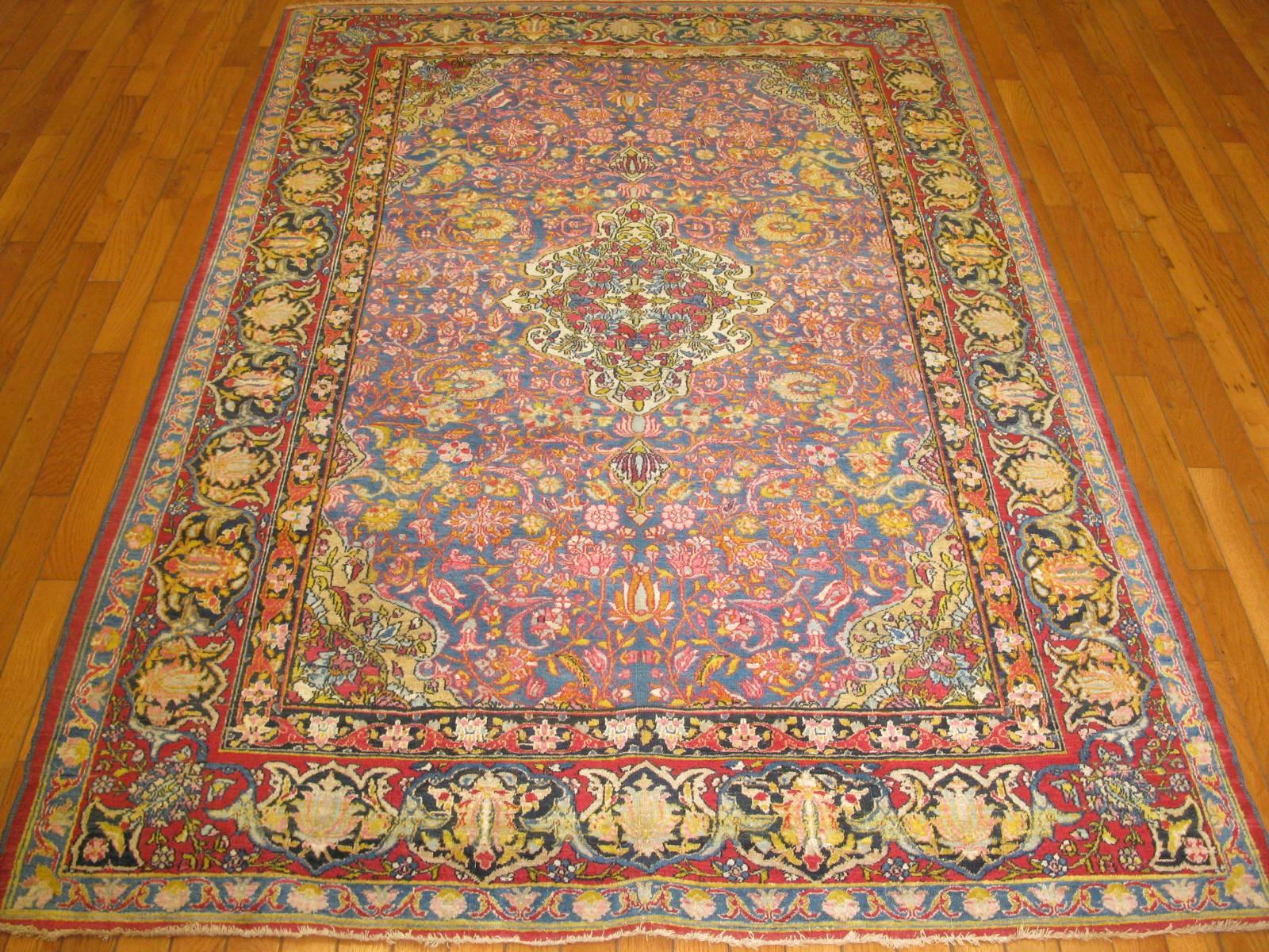 An outstanding antique hand-knotted Persian Isfahan rug with the traditional central and corner medallion design. Its beautiful intricate floral pattern is made on a light blue background and red border. The rug is in excellent condition and