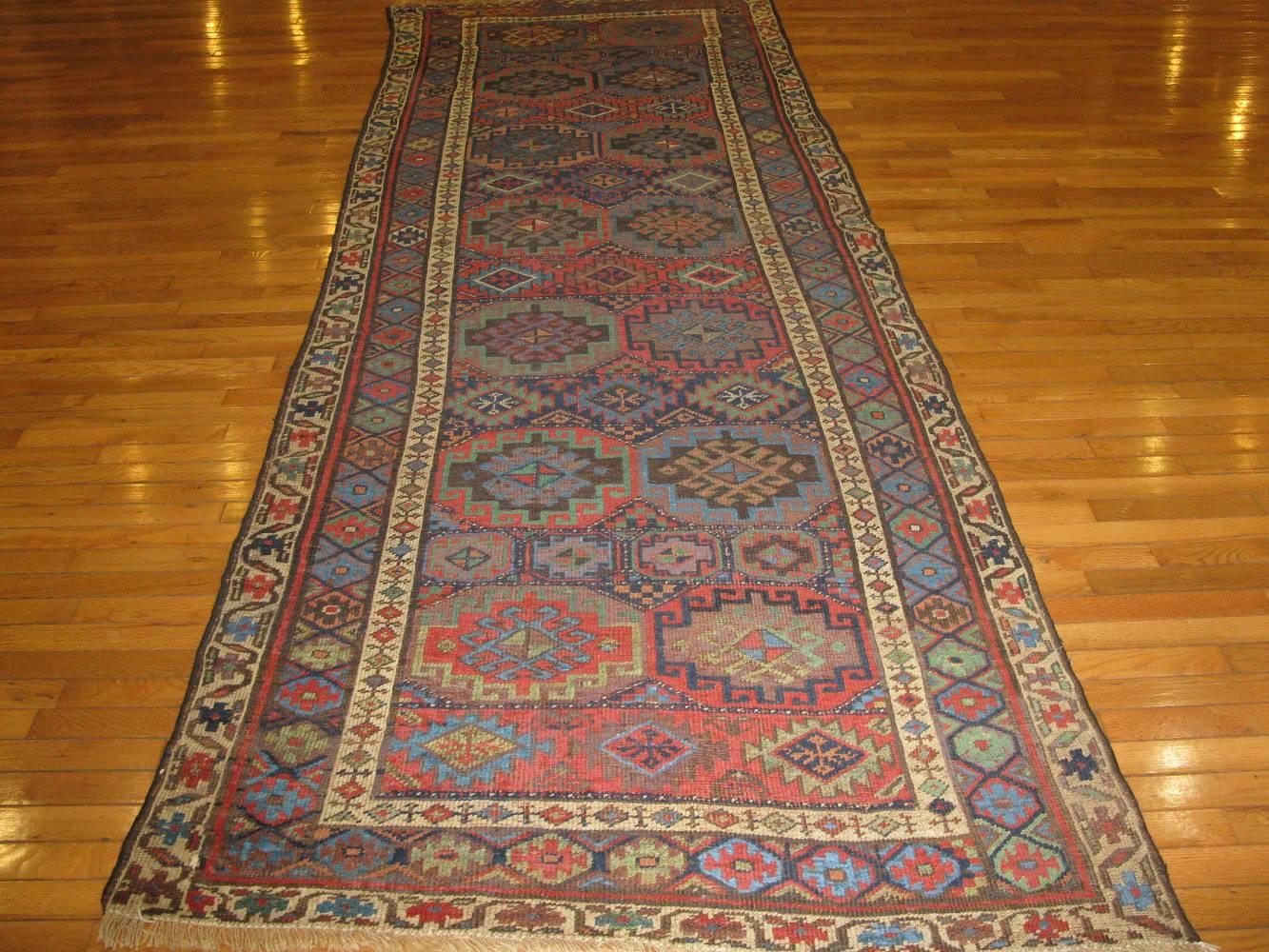 This is a beautiful antique wide and long hand-knotted Persian Kurdish runner rug with a tribal all-over pattern. The rug is made with all wool and natural dyes. 
It measures 4' x 11.7''.
