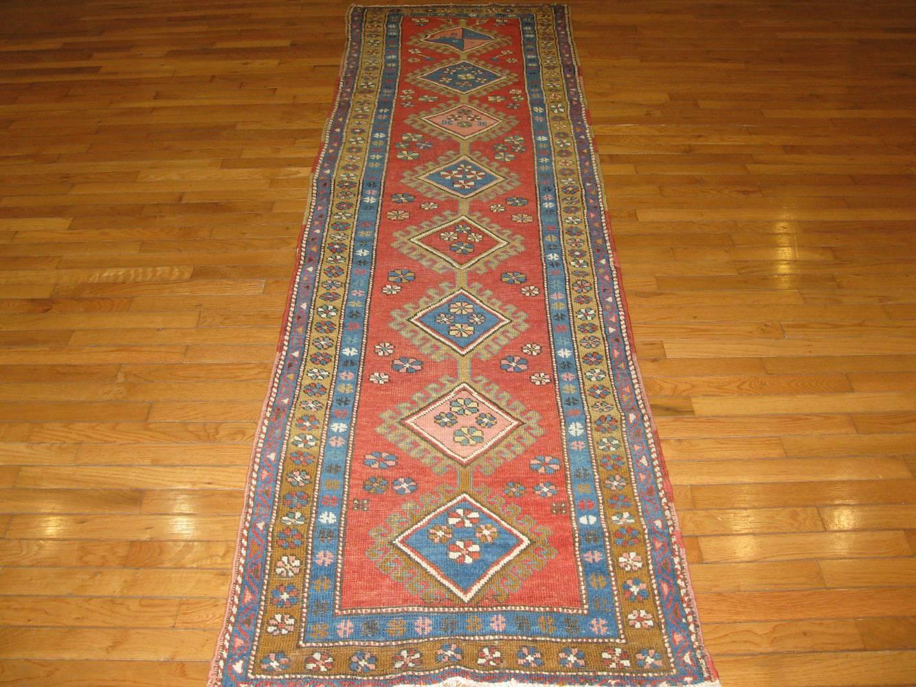 This is a beautiful and rare antique hand-knotted Persian Bakhshayesh runner rug in the traditional geometric design with multiple medallions on a soft red field. This is a perfect rug for any short hall or space. It measures 2' 7'' x 8' 10'' and in