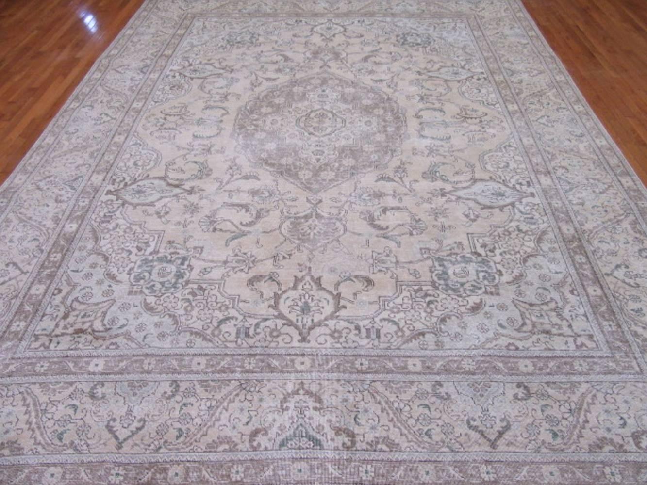 This is a beautiful hand-knotted distressed old Persian Tabriz rug. It has the cool contemporary and popular colors mixed with a more traditional pattern creating a great transitional rug to work with. It measures 9' 9'' x 12' 8'' and in good shape.