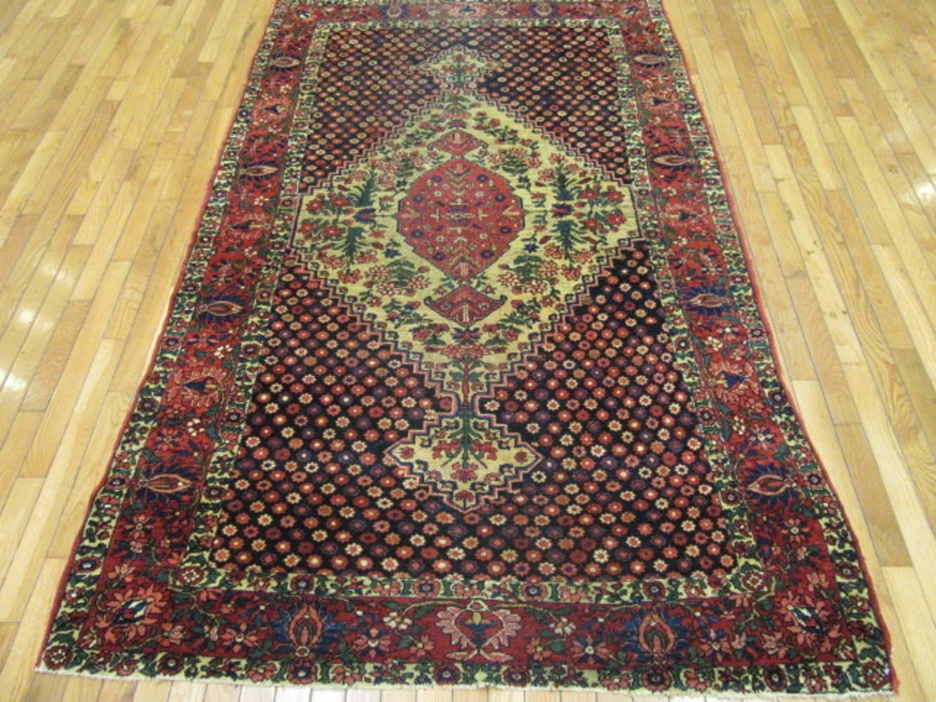This is a finely hand-knotted antique Persian rug from the Baktiary region of the western mountains in Iran. The rug though nomadic has an intricate pattern with a large central medallion in ivory on a dark navy color background. It is made with