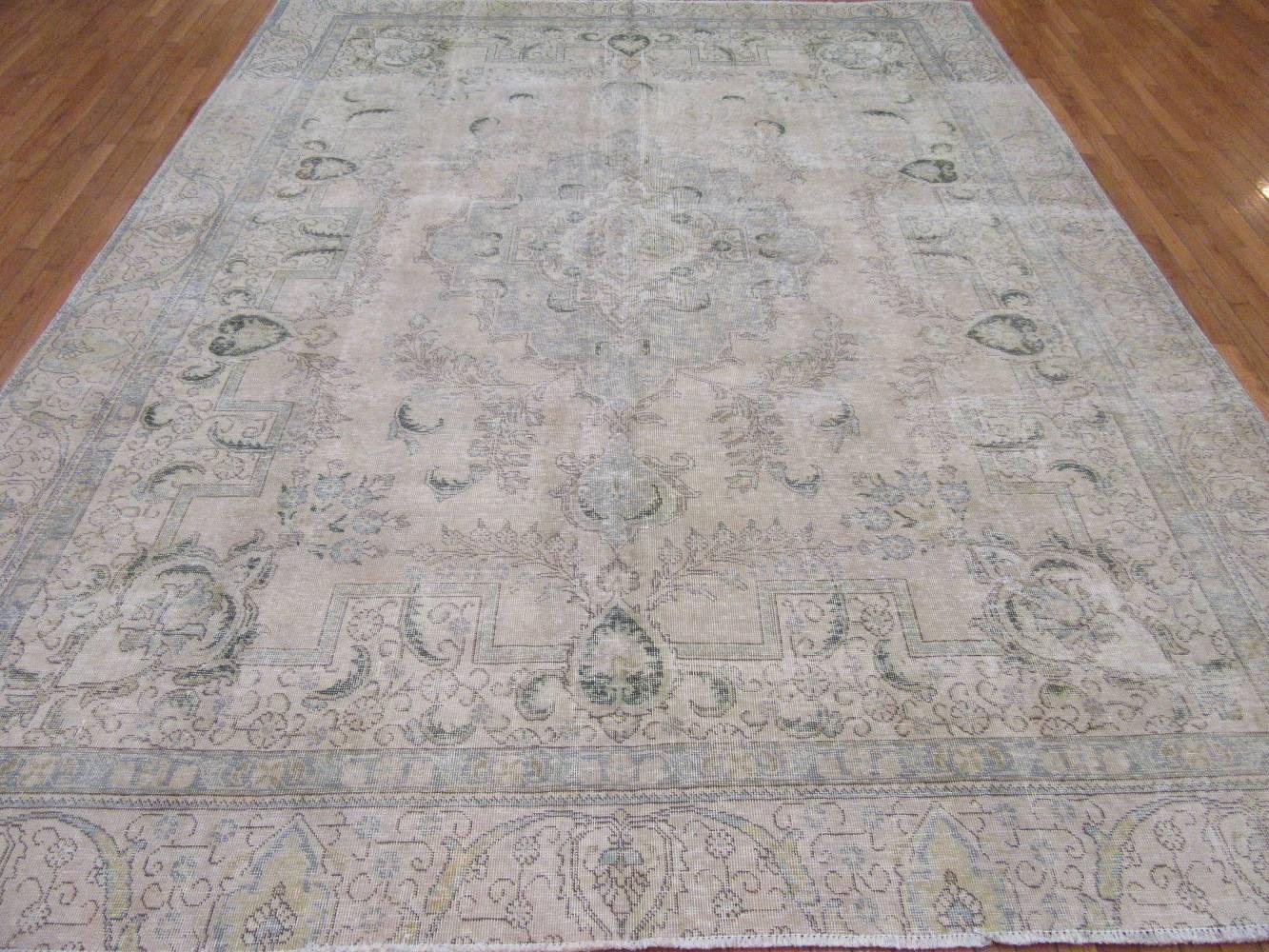 This is an old hand-knotted Persian Tabriz rug. It has been stripped down to a distressed look and white washed to achieve a soft color finish. The rug measures 9' 1'' x 11' 5''.