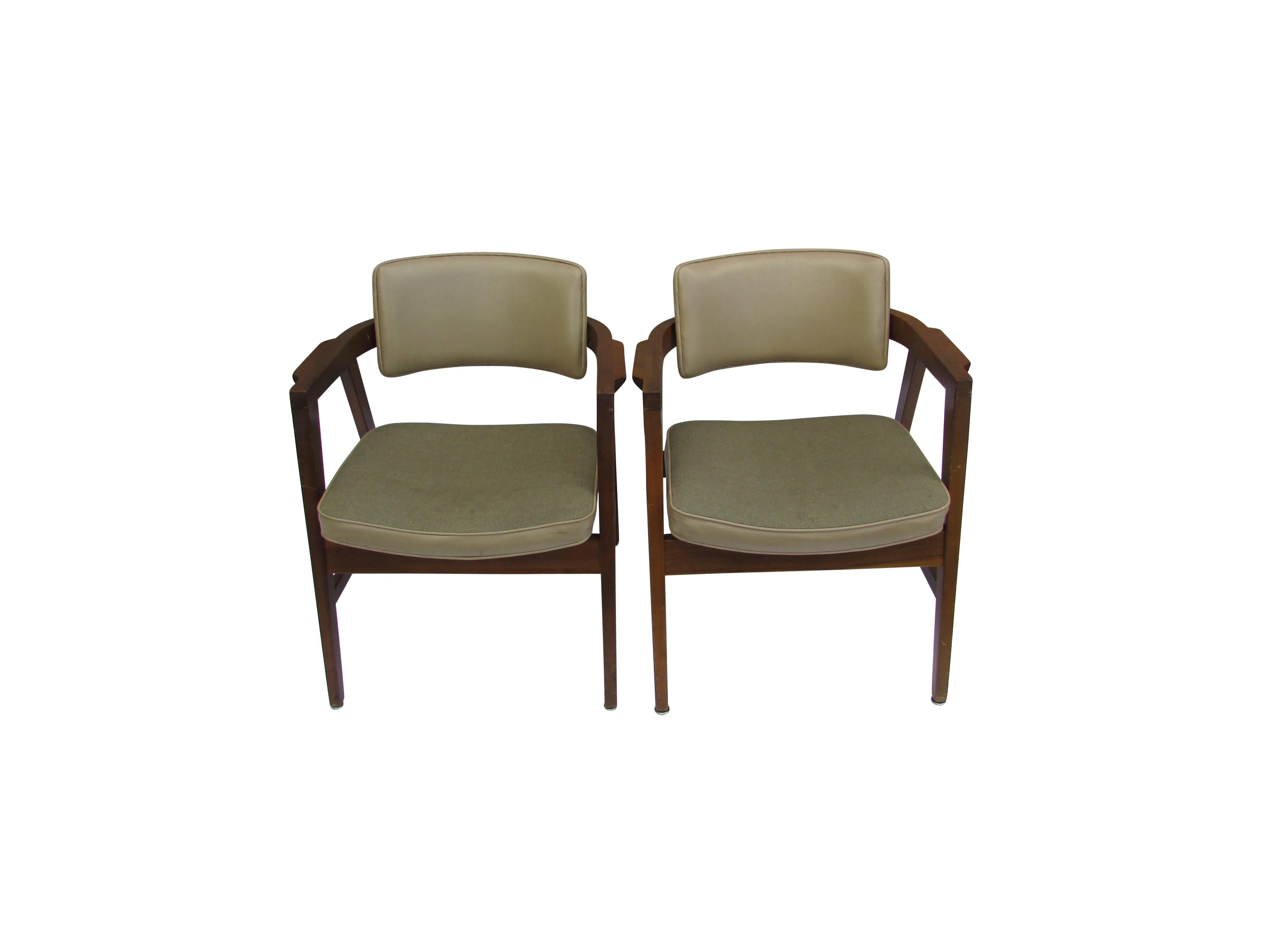 This is a pair of walnut armchairs with great lines by The Gunlocke Company, Inc. On the underside of the seat, the original manufacturers labels are still intact. On the back side of the either chair is a US Department of Labor label. Upholstery is