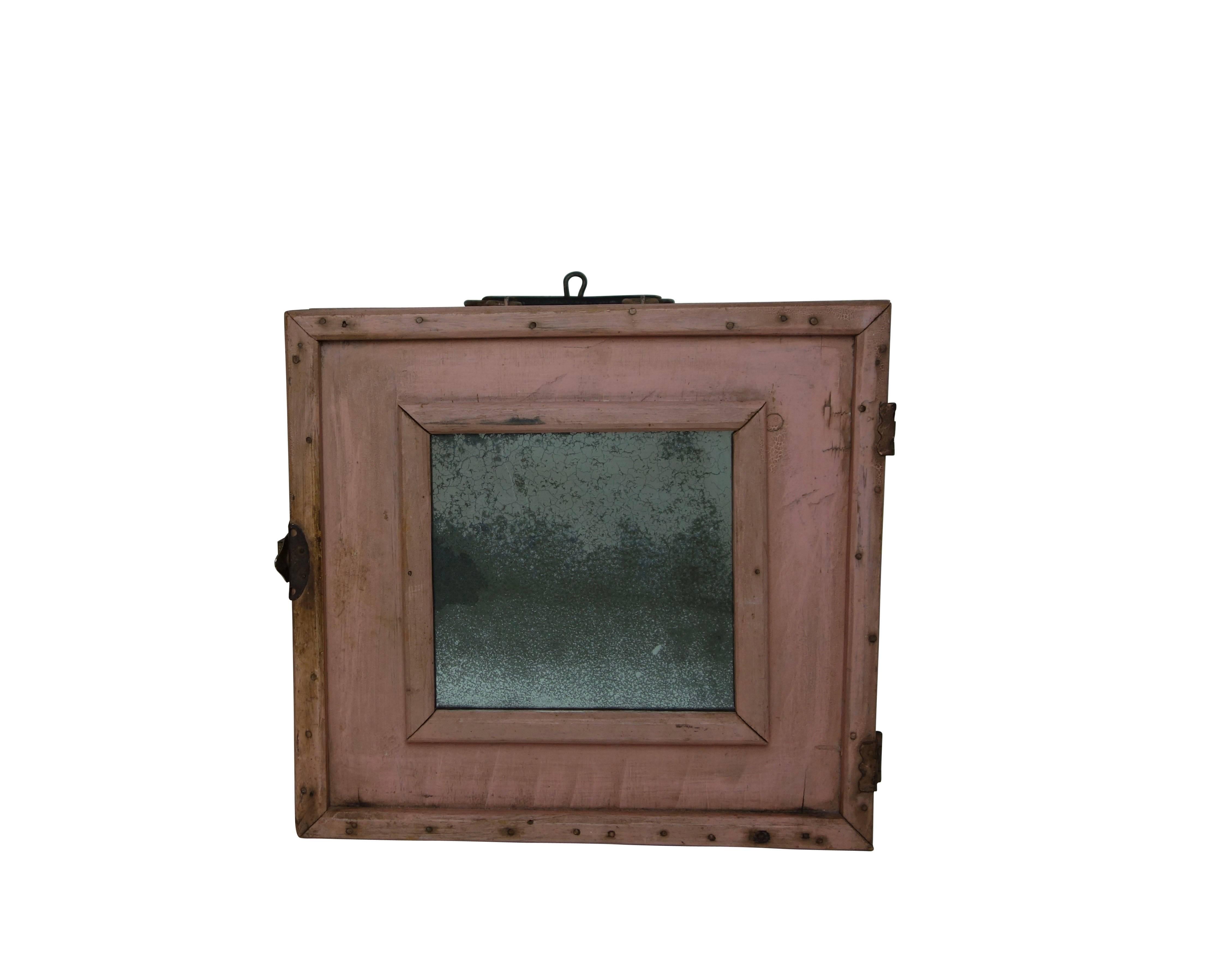 This is a wonderful pink traveling make-up case with a perfectly foxed mirror. There's a metal hook so that it can be wall-mounted, along with a handle for carrying. The hardware, rusty nailheads, and crackled pink paint give this little cabinet