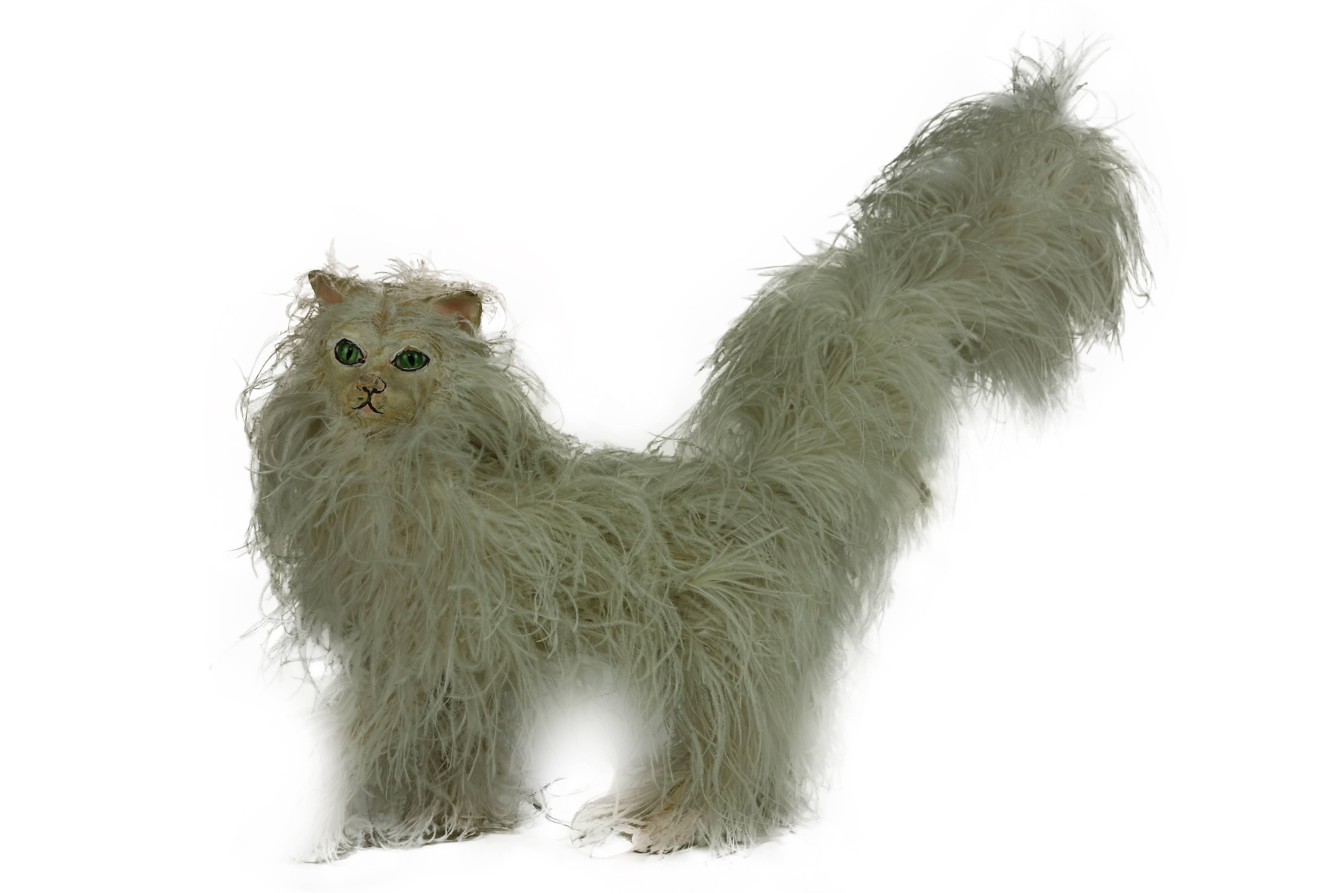 This is an unusual papier mâché cat made of ostrich feathers from a millinery shop in Portland, Oregon, circa 1930. The face is hand-painted with electric green glass eyes. The inside of the body is filled with some material to give it weight.