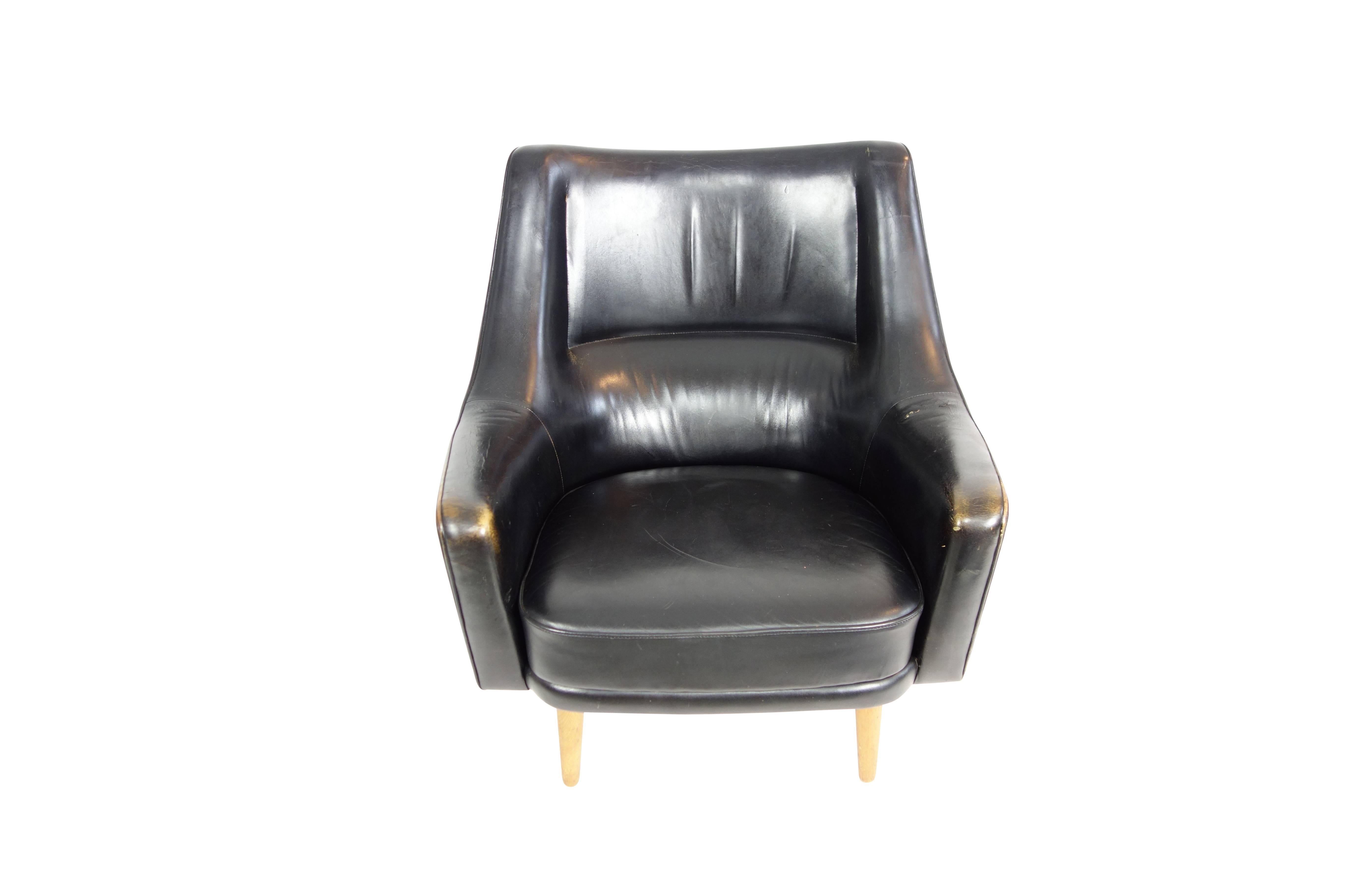 This is a sleek lounge chair by Ib Kofod-Larsen in its original black leather upholstery, circa 1950.