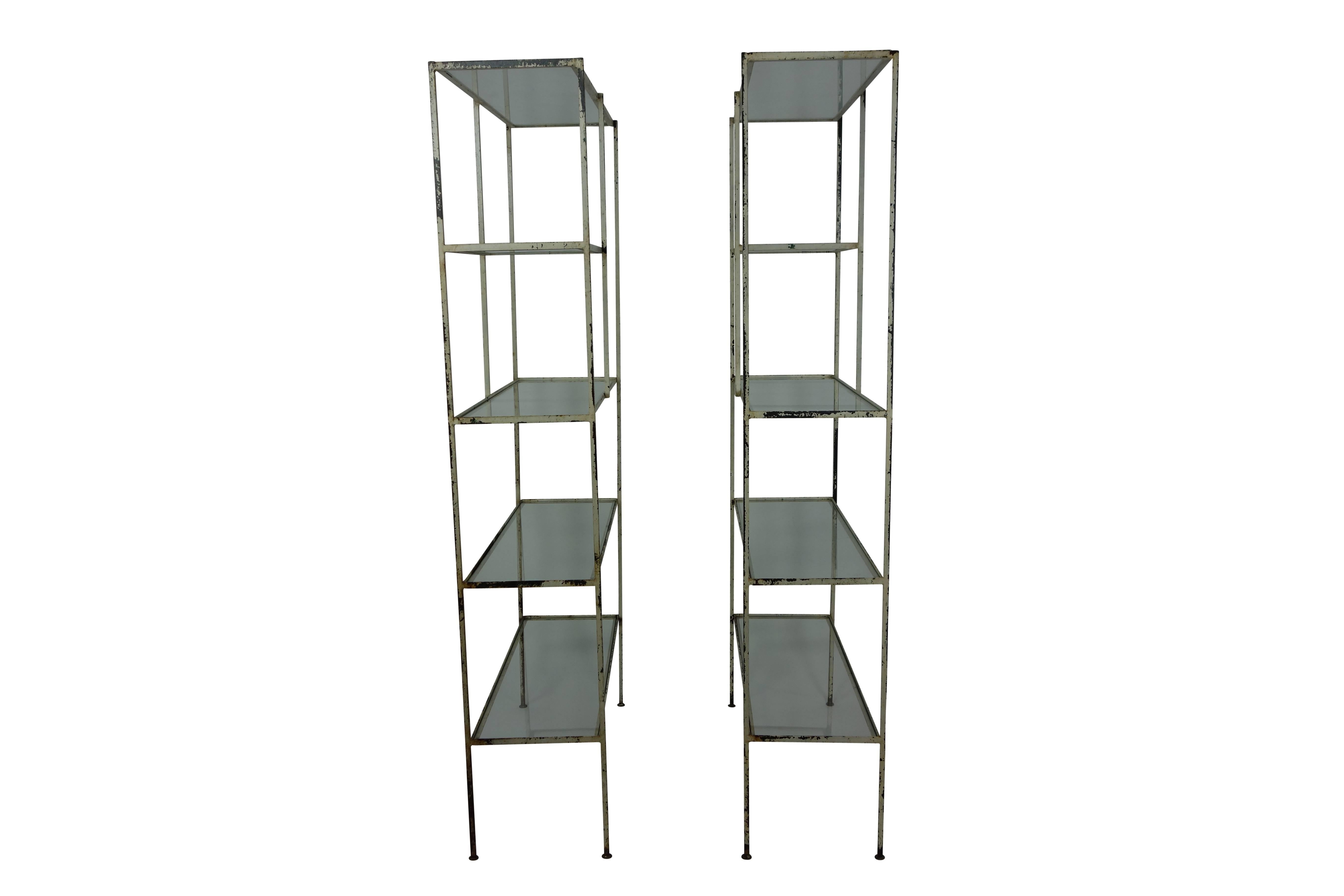 These are a wonderful pair of bookshelves with painted white steel frames and original glass shelves, circa 1940. Under the white paint you can see the slightest hint of the color green it was once painted with.