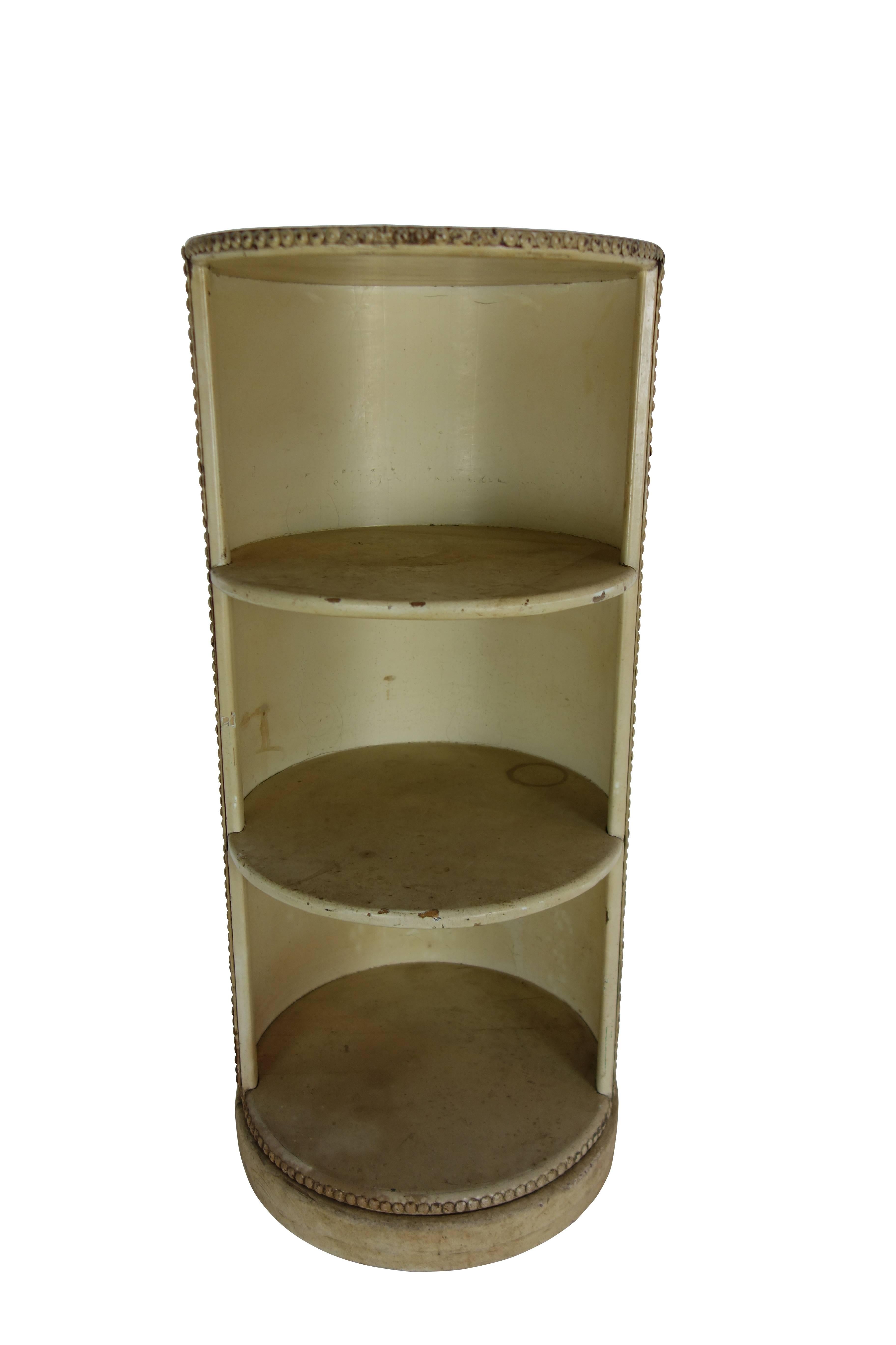 This is a unique circular three-tiered shelf wrapped in cream leather with rivet detail, circa 1920.