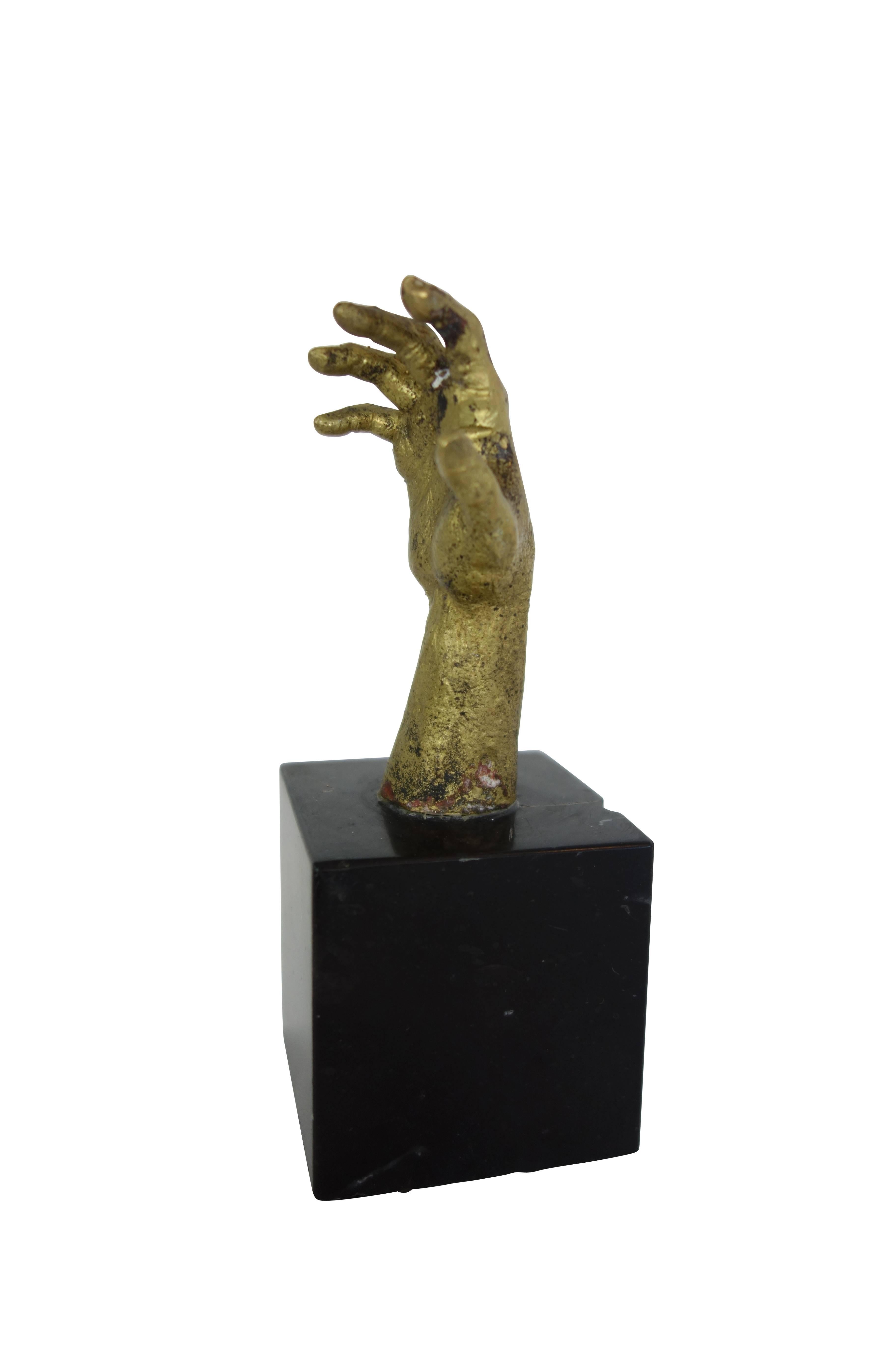 This is a small brass hand sculpture on a black marble base.