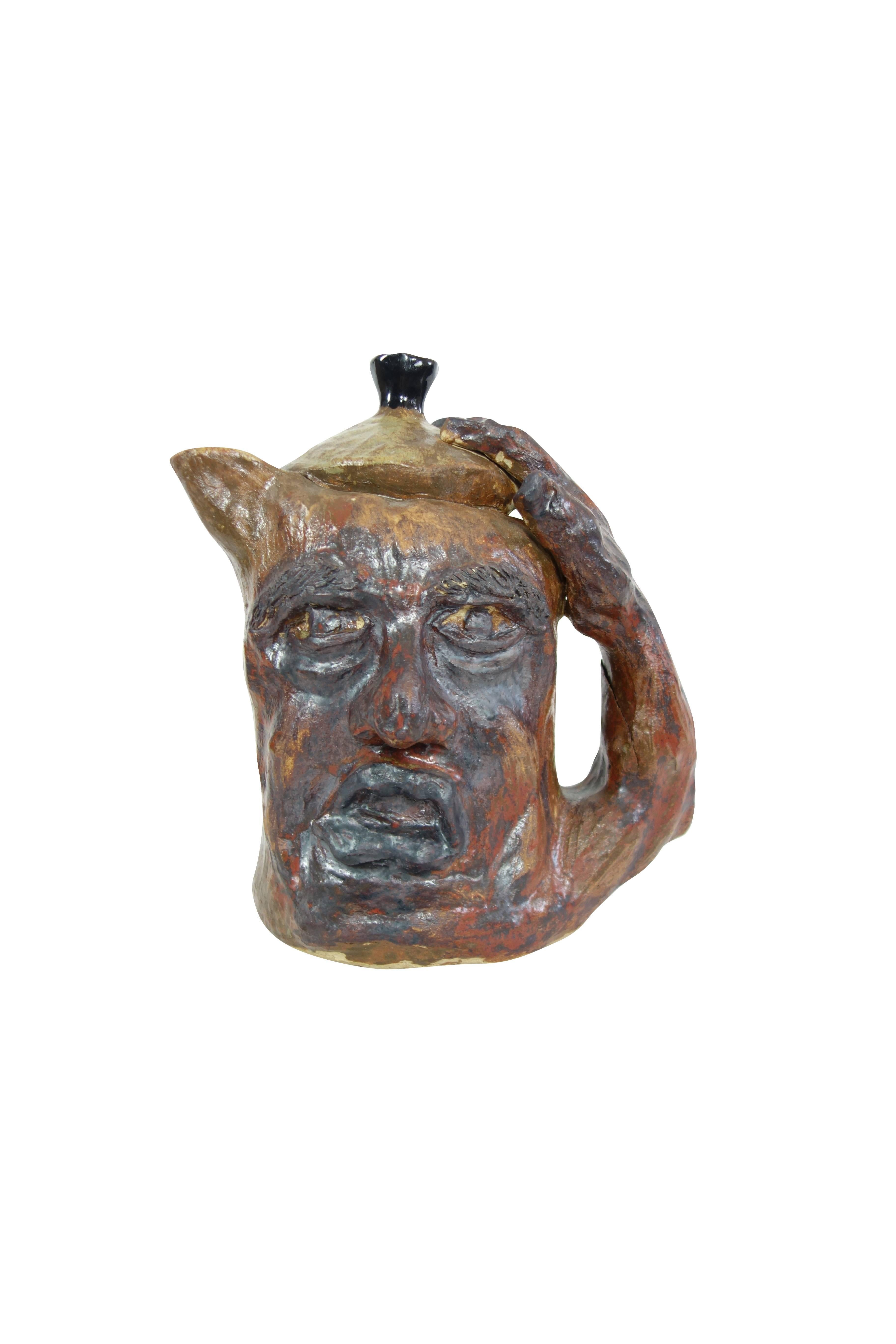 This is a vintage grotesque face jug from a pottery studio in Buffalo, New York. This is all one piece, the lid does not lift off of the jug.