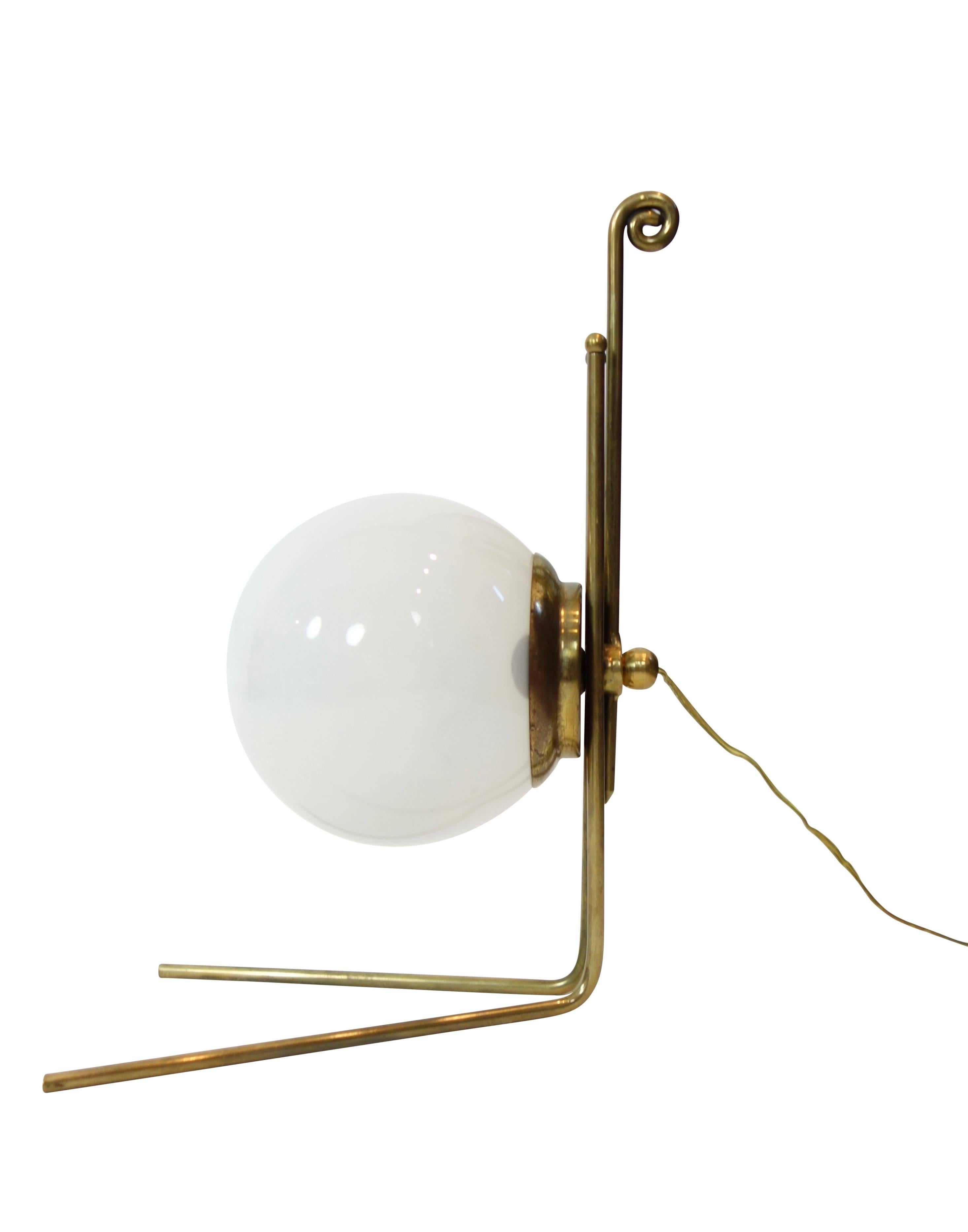 This is a unique and lovely French table lamp, circa 1930. A milk glass globe is supported by a dainty brass base that takes the form of a fiddlehead fern at the very top.