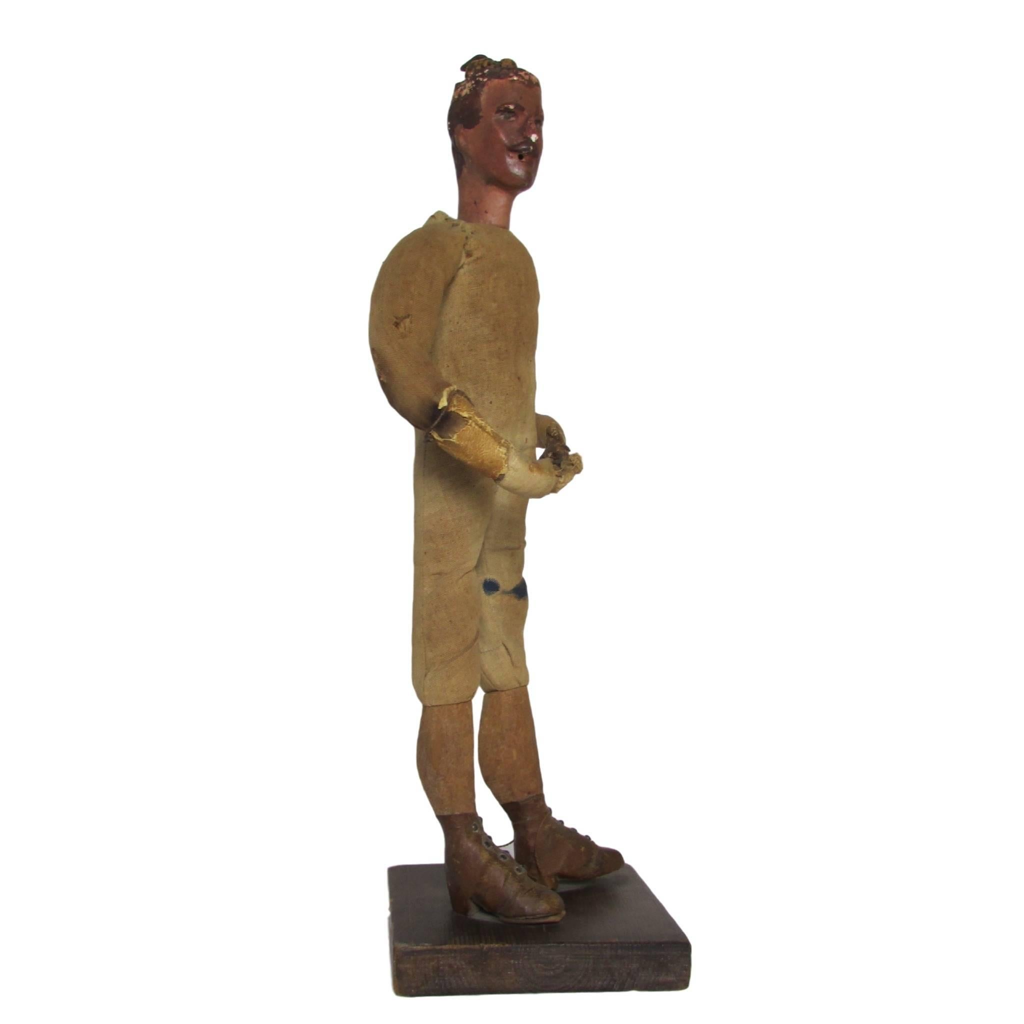 This is a rare and unique hand carved French figurine of a mustached man in leather boots on a wood stand.  His body is made of hand sewn muslin that has been stuffed with wood shavings. His forearms and hands are wrapped in leather that is sewn to