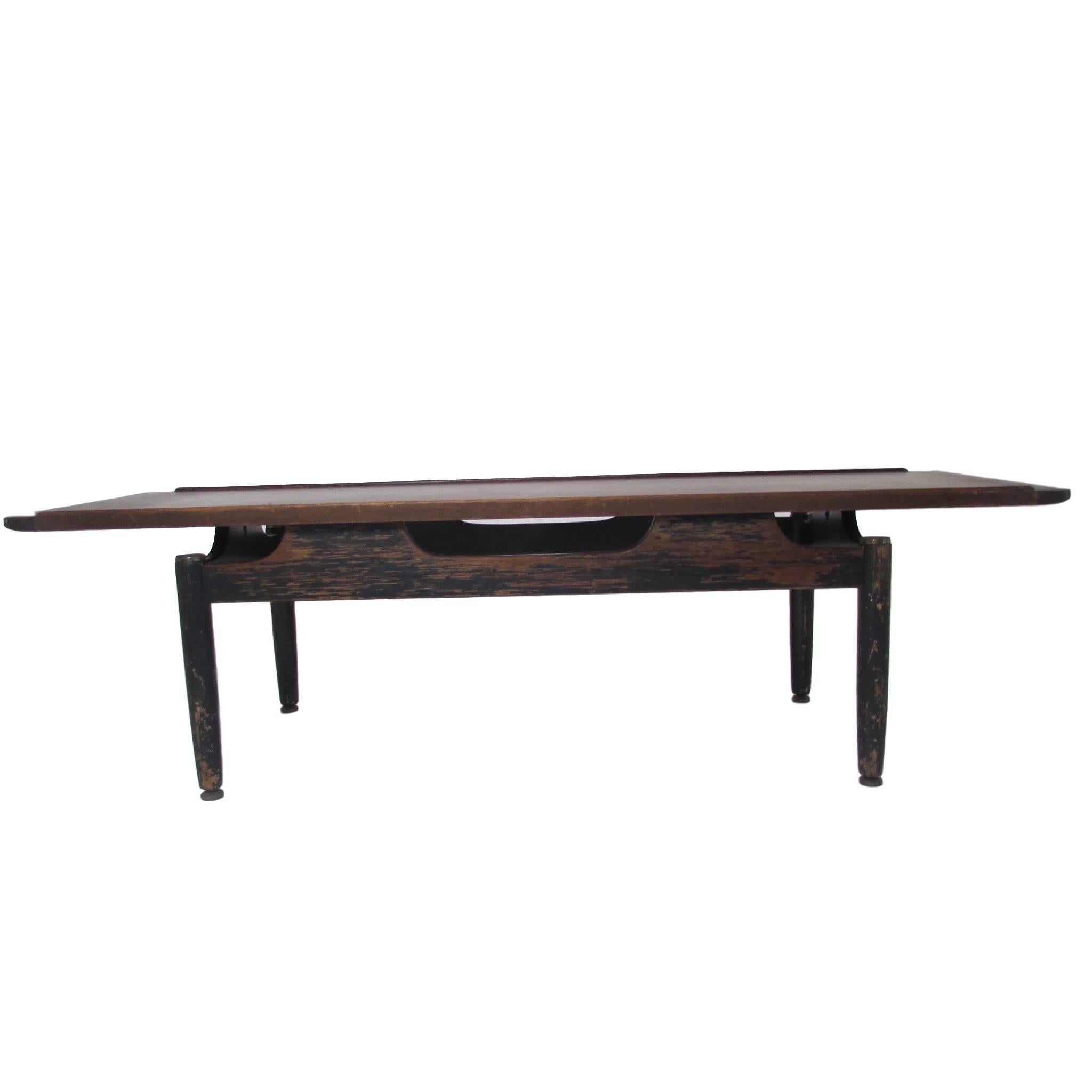 This is a mid century teak G-Plan Long John coffee table.  Having a modern sleek design, the base is painted black and has brass caps on the tops of each leg.  