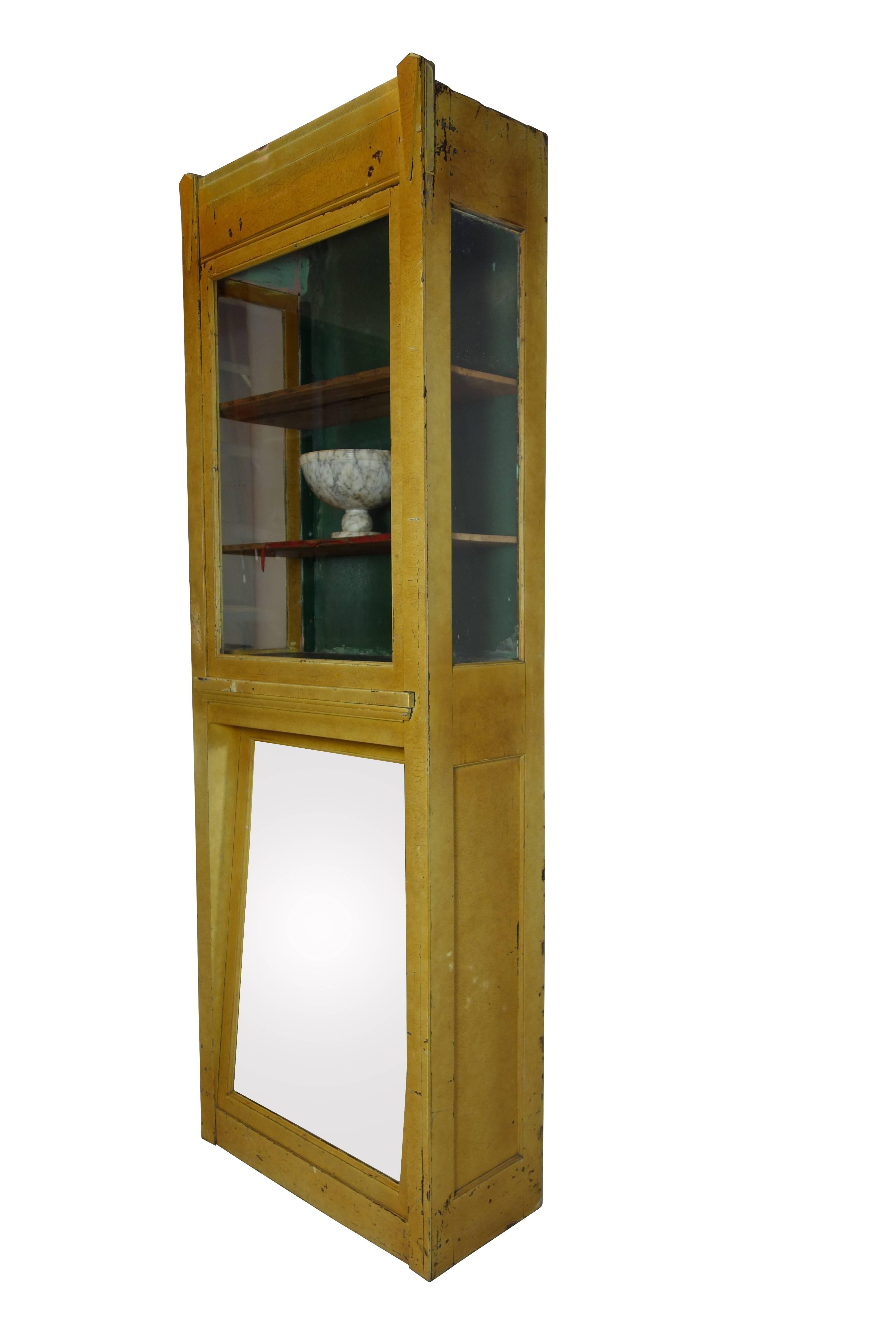 This is an Art Deco boot display case in its original paint from a department store in the Midwest. The upper display portion of the case is lighted, illuminating the objects placed inside. The mirror on the bottom of the cabinet is angled so the