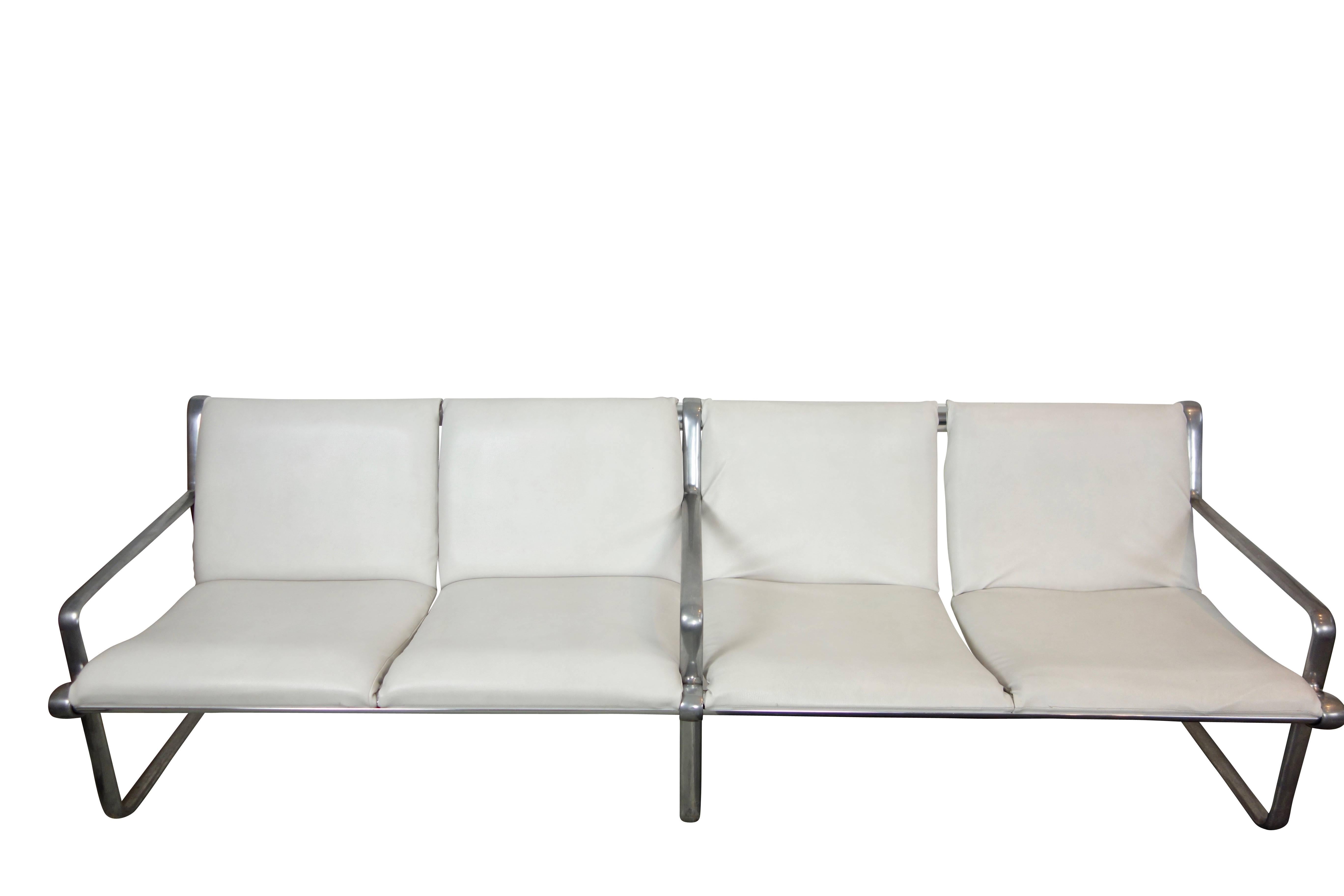 This is a four-seat Hannah and Morrison airport sling sofa produced by Knoll with aluminum frame and white leather upholstery.