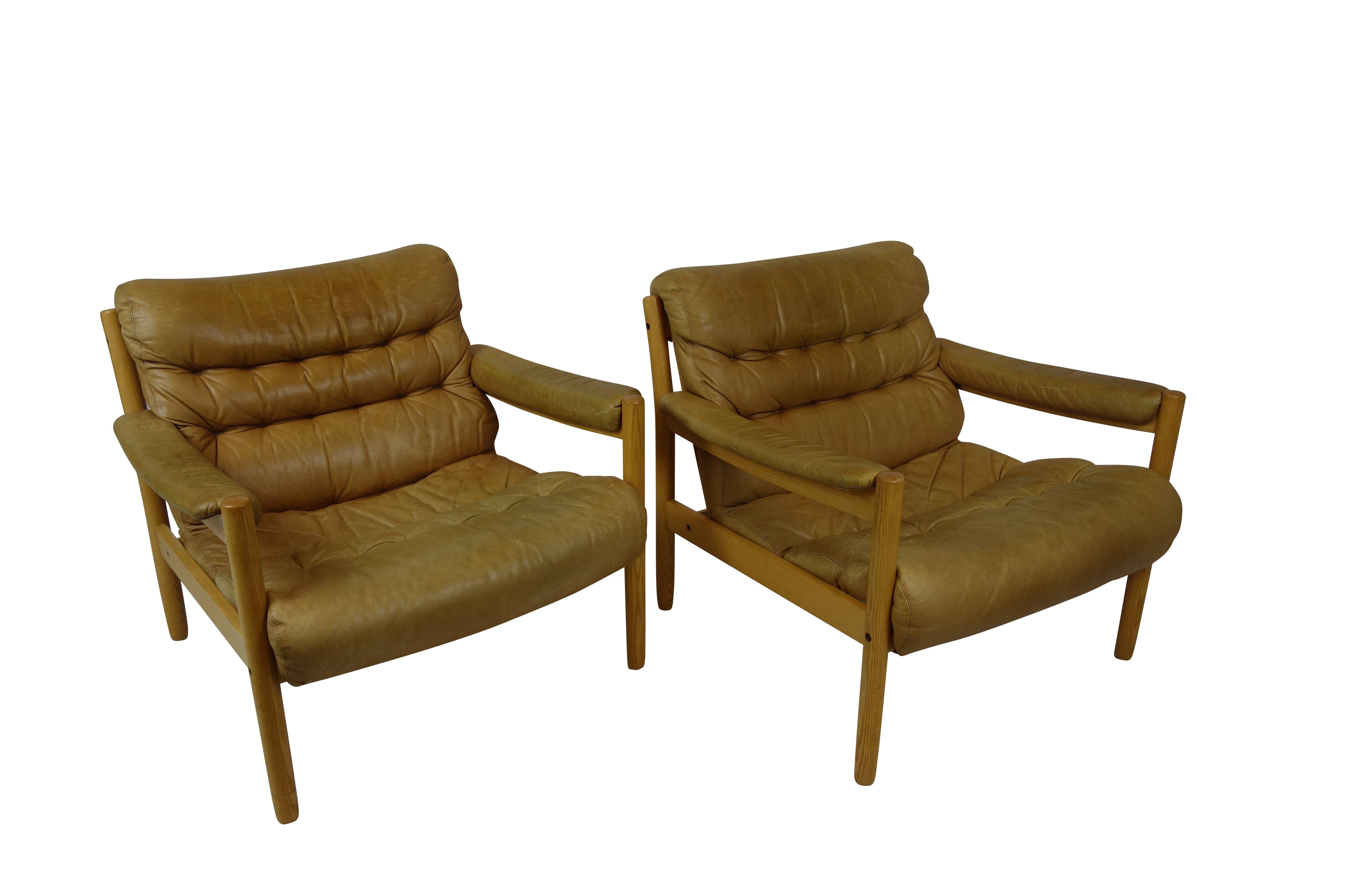 This is a pair of easy chairs in beechwood by Bruno Matthson produced for Dux, in their original tan leather upholstery.