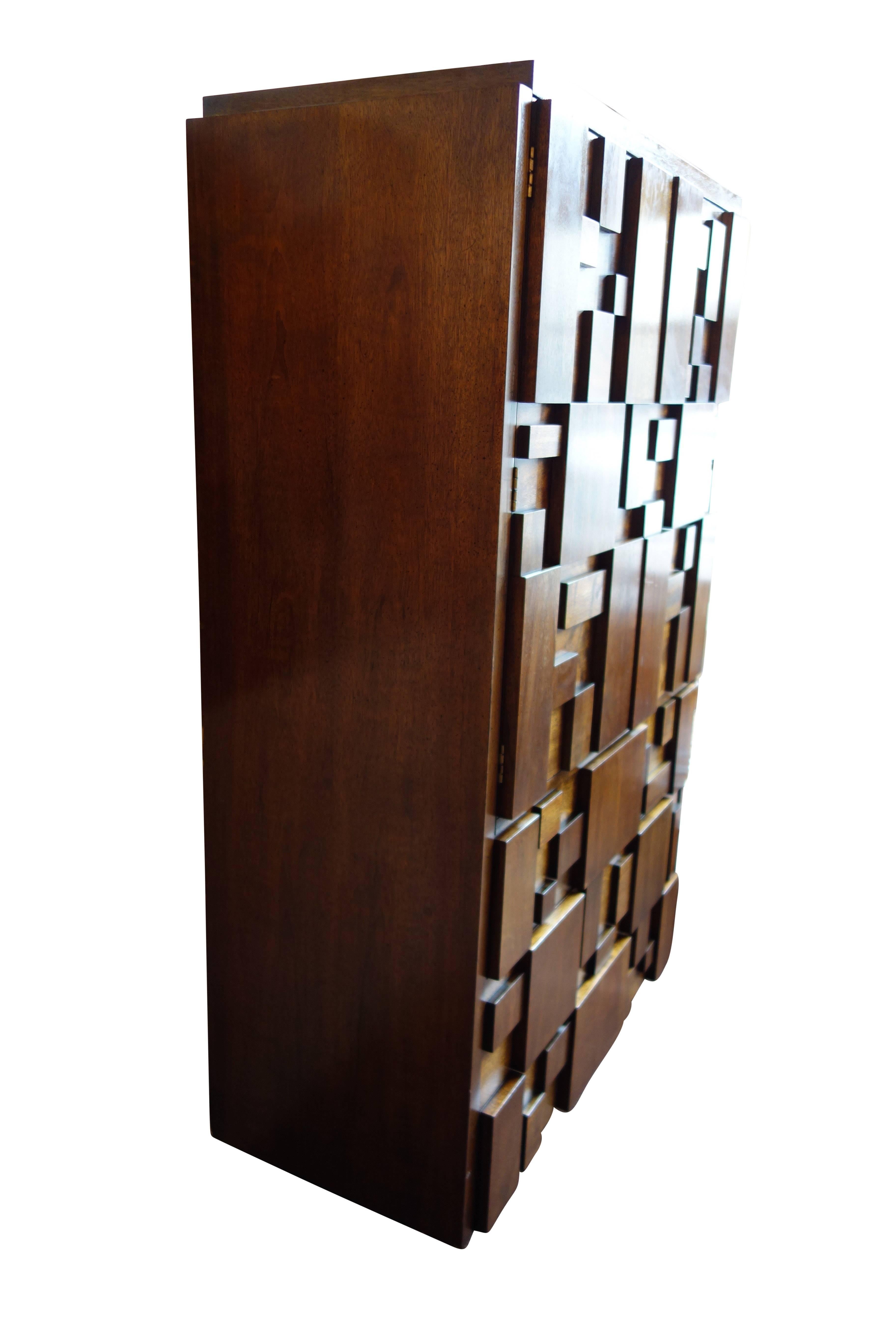 This is a Lane brutalist mosaic high boy cabinet, circa 1970. The upper cabinet doors open up to reveal one drawer and divided open shelving. The lower portion of the cabinet has three drawers. Also available is the matching nine-drawer dresser,