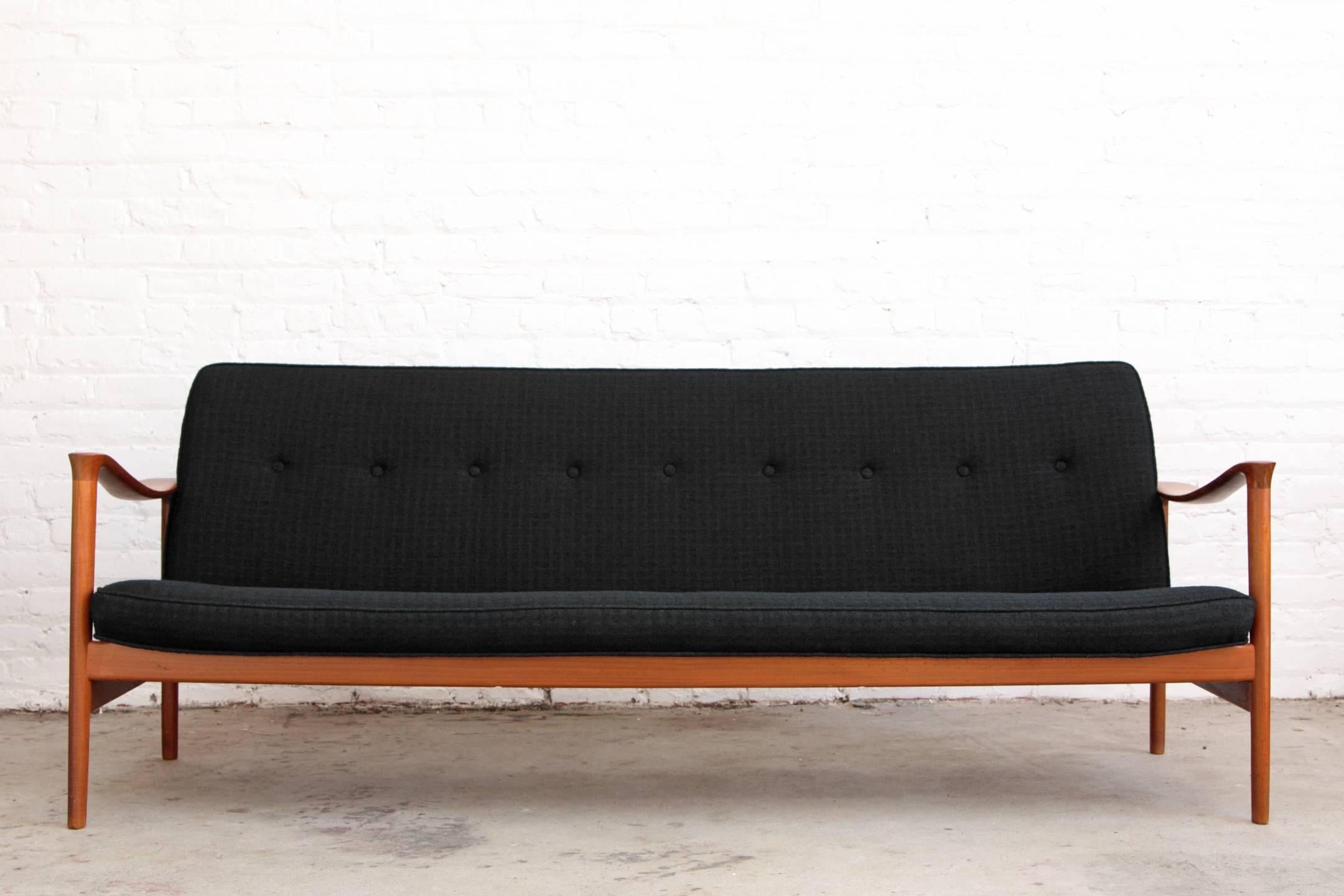 Scandinavian Modern sofa by Torbjørn Afdal. Made in Norway. Solid teak sculpted frame with textured black wool upholstery.