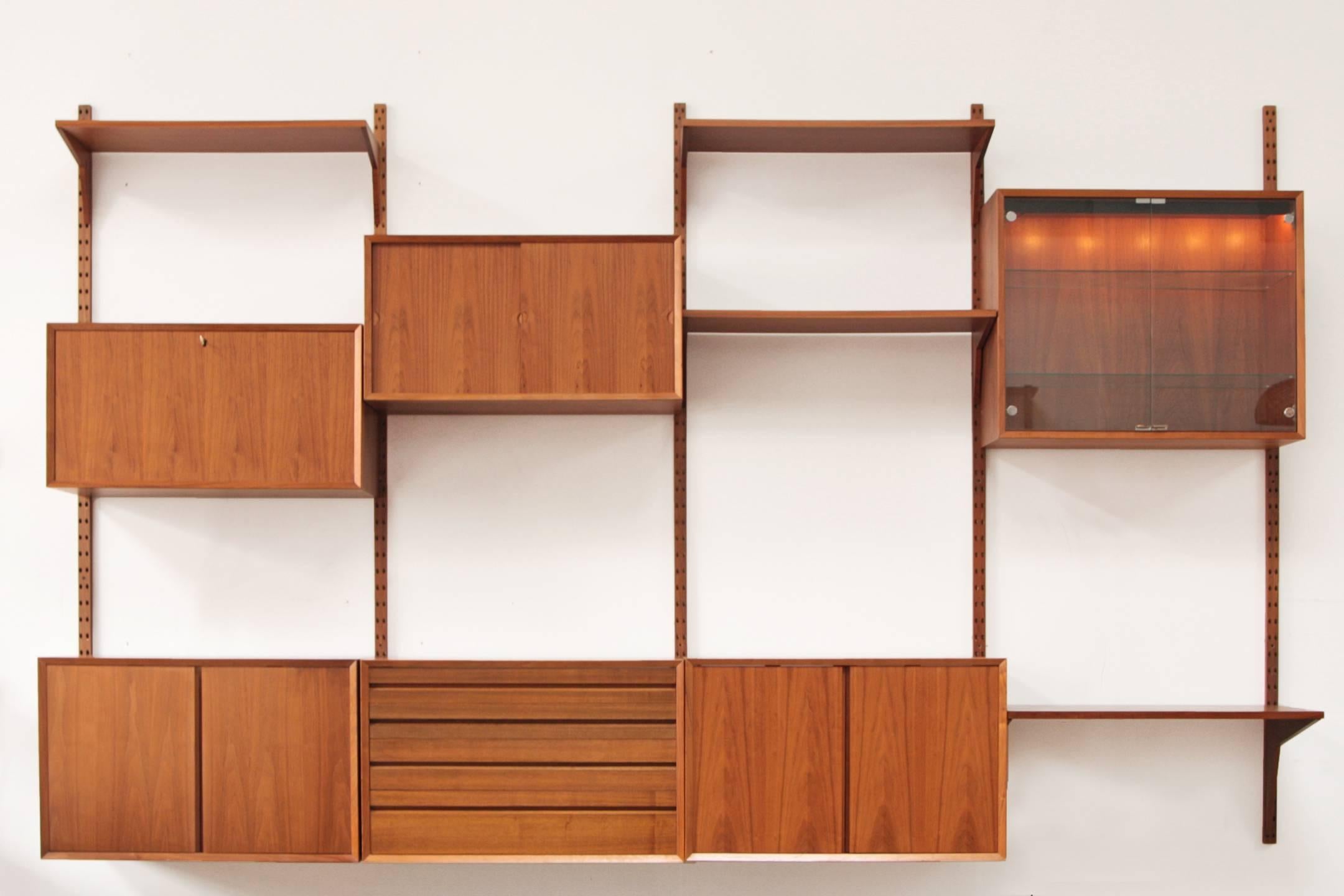 Four bay Danish wall unit designed by Poul Cadovius. Royal system with solid teak brackets. Four wood rails that suspend six cabinets and four shelves. A drop down bar cabinet with key and record storage cabinet also. A great multifunctional piece