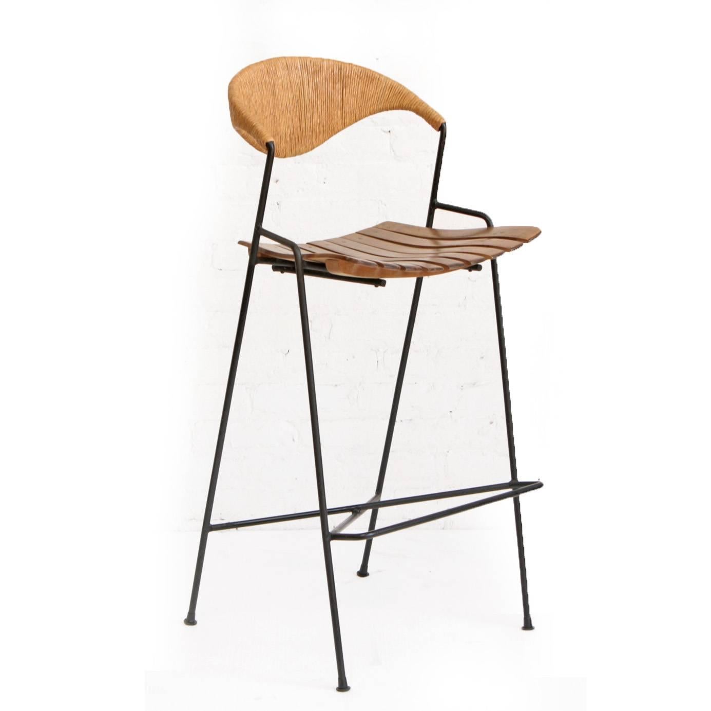 Set of four bar stools by American Mid-Century Modern designer Arthur Umanoff. Minimalist wrought iron frames with wood slat seats and wrapped paper cord backrests.