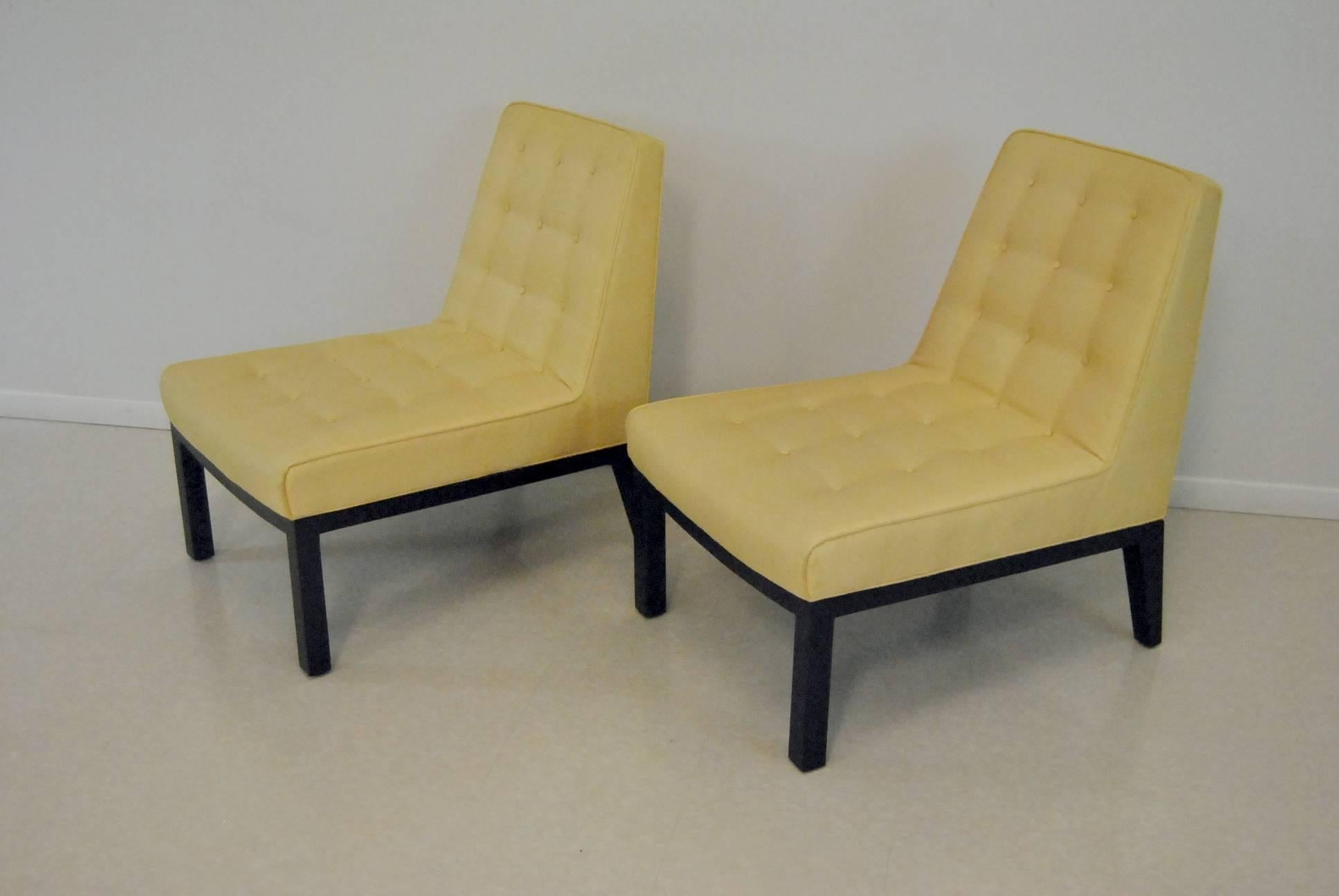 Beautiful pair of slipper chairs by Edward Wormley for Dunbar. Chairs have a mahogany frame with ebonized finish. Upholstery is a butter yellow silk with tufted back and seat. Lumbar pillows complete the look.