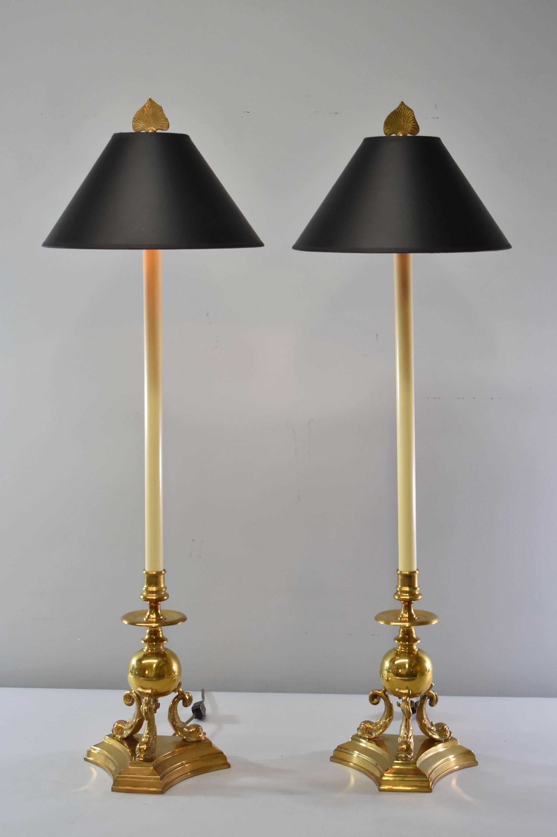A beautiful pair of tall brass buffet lamps by Chapman, 1987. They feature a three dolphins with the base resting atop their tails. It also has a dolphin tail finial. Very good condition with very minimal wear.