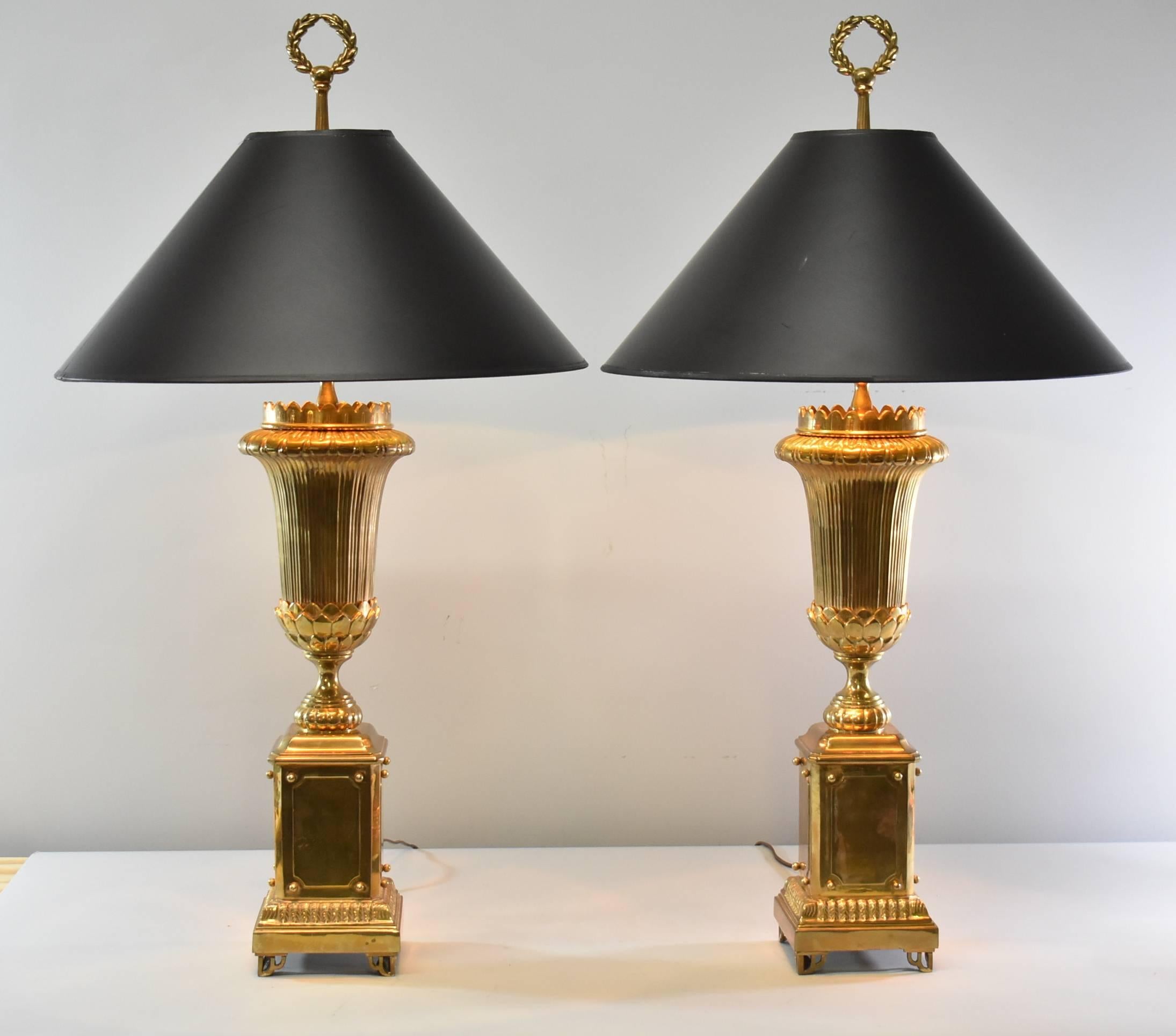 An outstanding pair of brass lamps by Chapman. These lovely lamps feature a square shape base with a torch form and a wreath finial. Sure to add style and elegance to any room. Very good condition with some minor wear to the brass.
