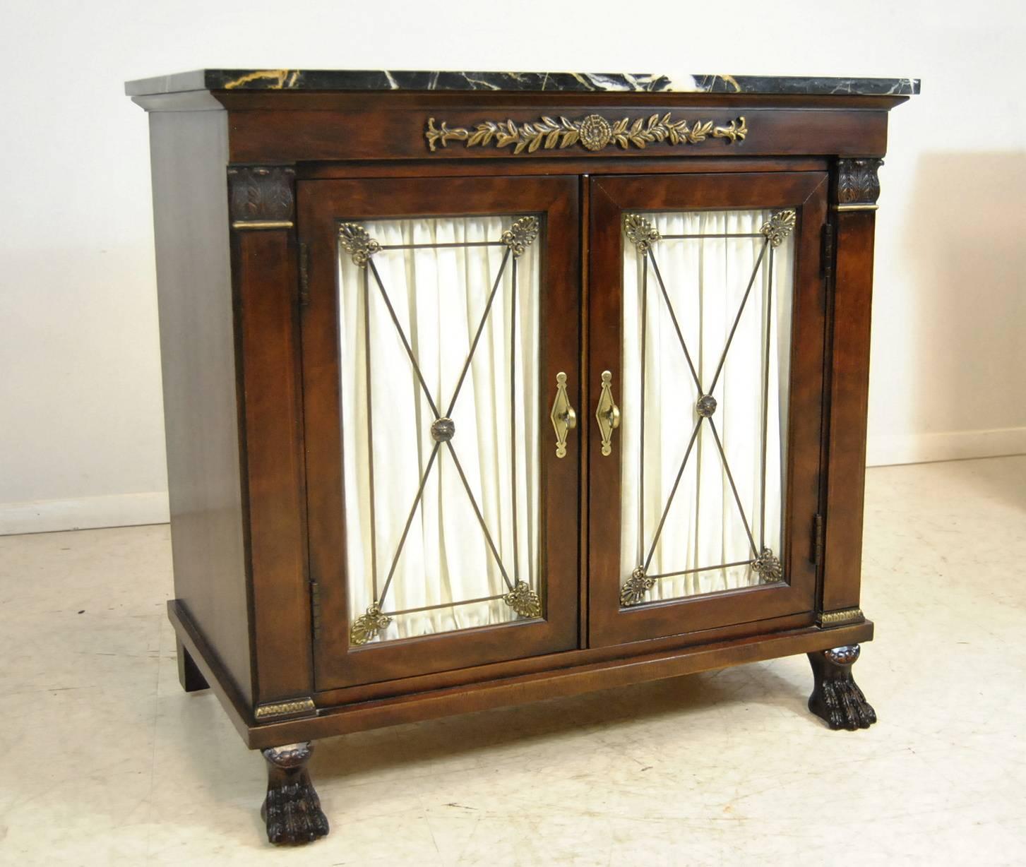 A beautiful pair of marble top double door Empire style cabinets by Henredon. These are the New St Laurent cabinets and feature a distressed dark walnut finish with applied carvings at front top. Double doors have decorative metal inserts which are