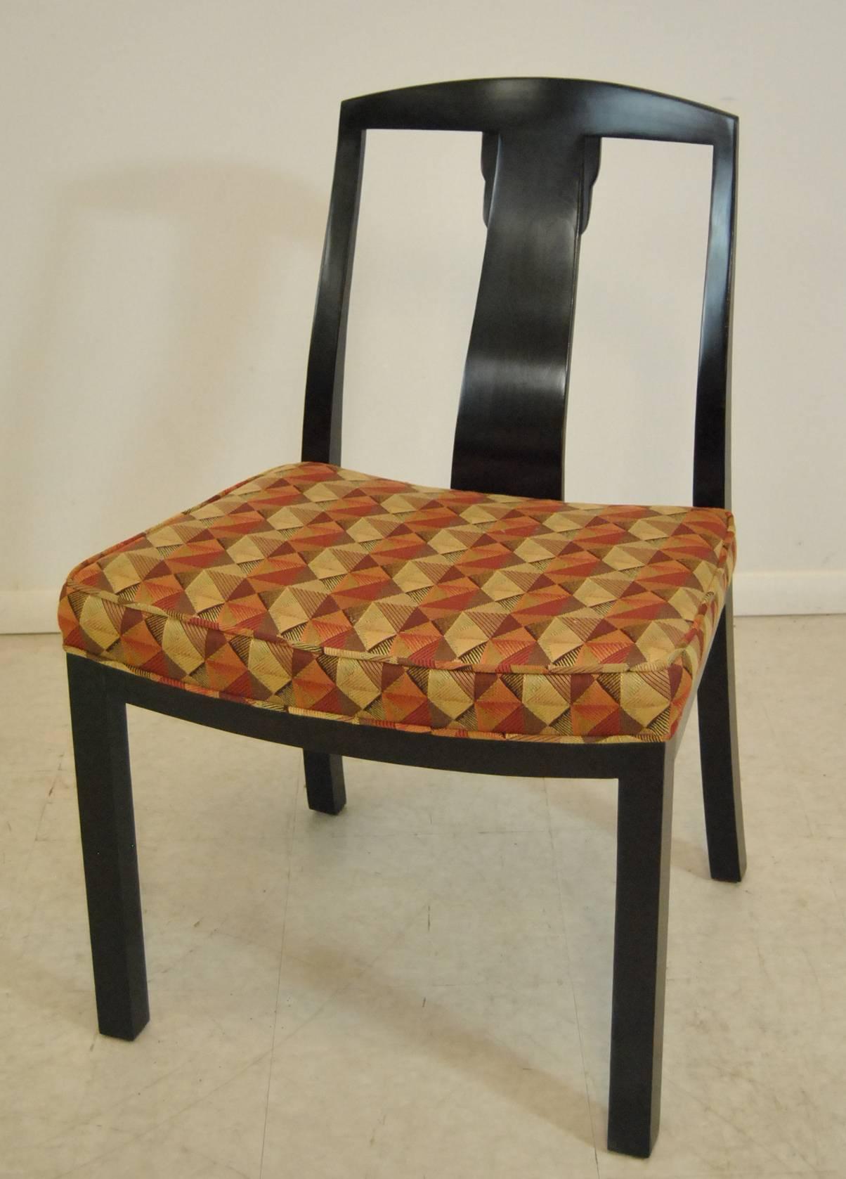 An unusual set of six dining chairs by Baker. Chairs are done in a dark espresso finish with upholstered seats. Unusual splat with Asian flair adds interest to the clean lines of these Mid-Century Modern chairs.