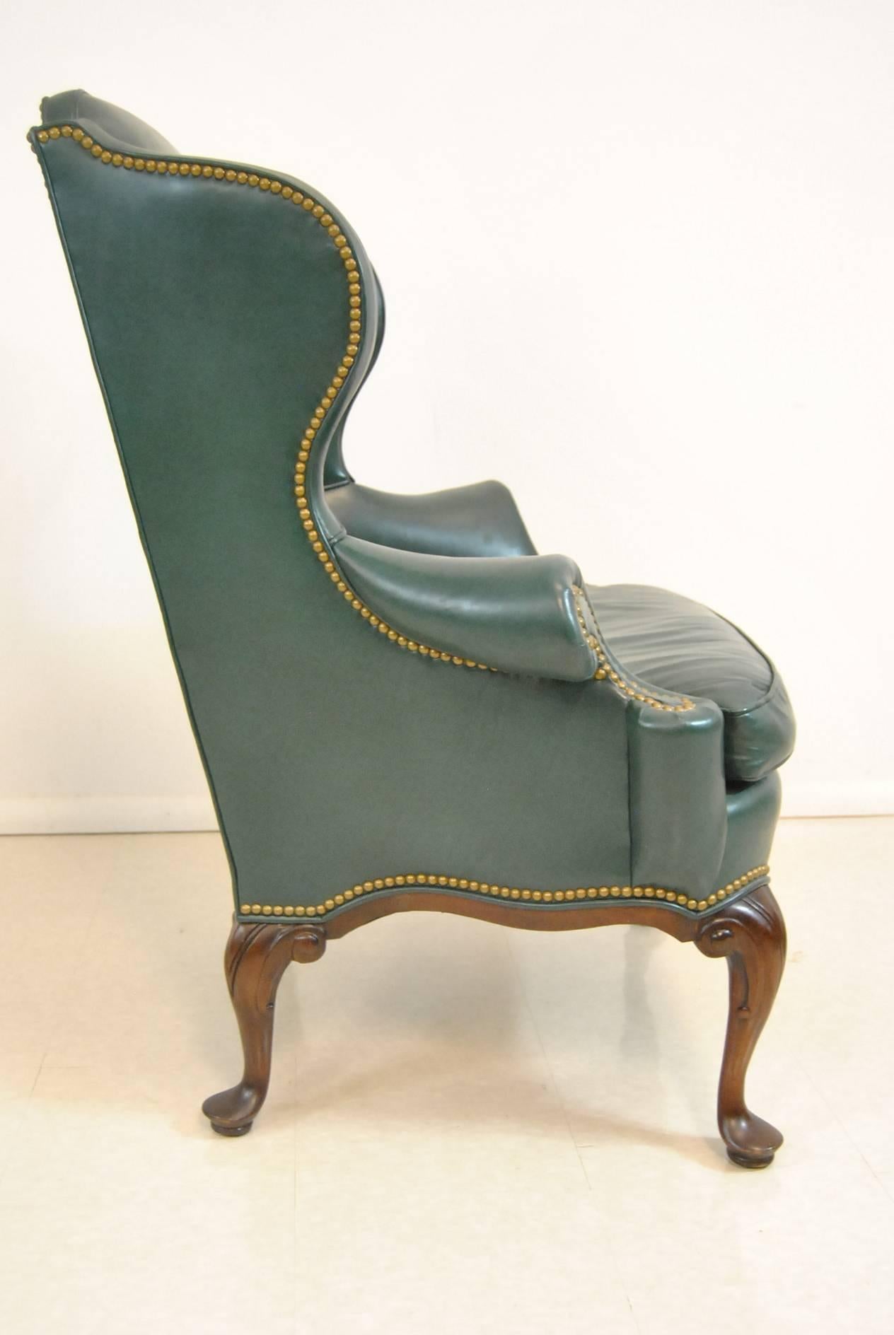 A handsome wingback chair by Hancock & Moore. This beautiful piece features green leather upholstery, brass nailhead trim and a walnut frame. Sophisticated and stylish this chair will make a statement in any room of your home. Very good condition