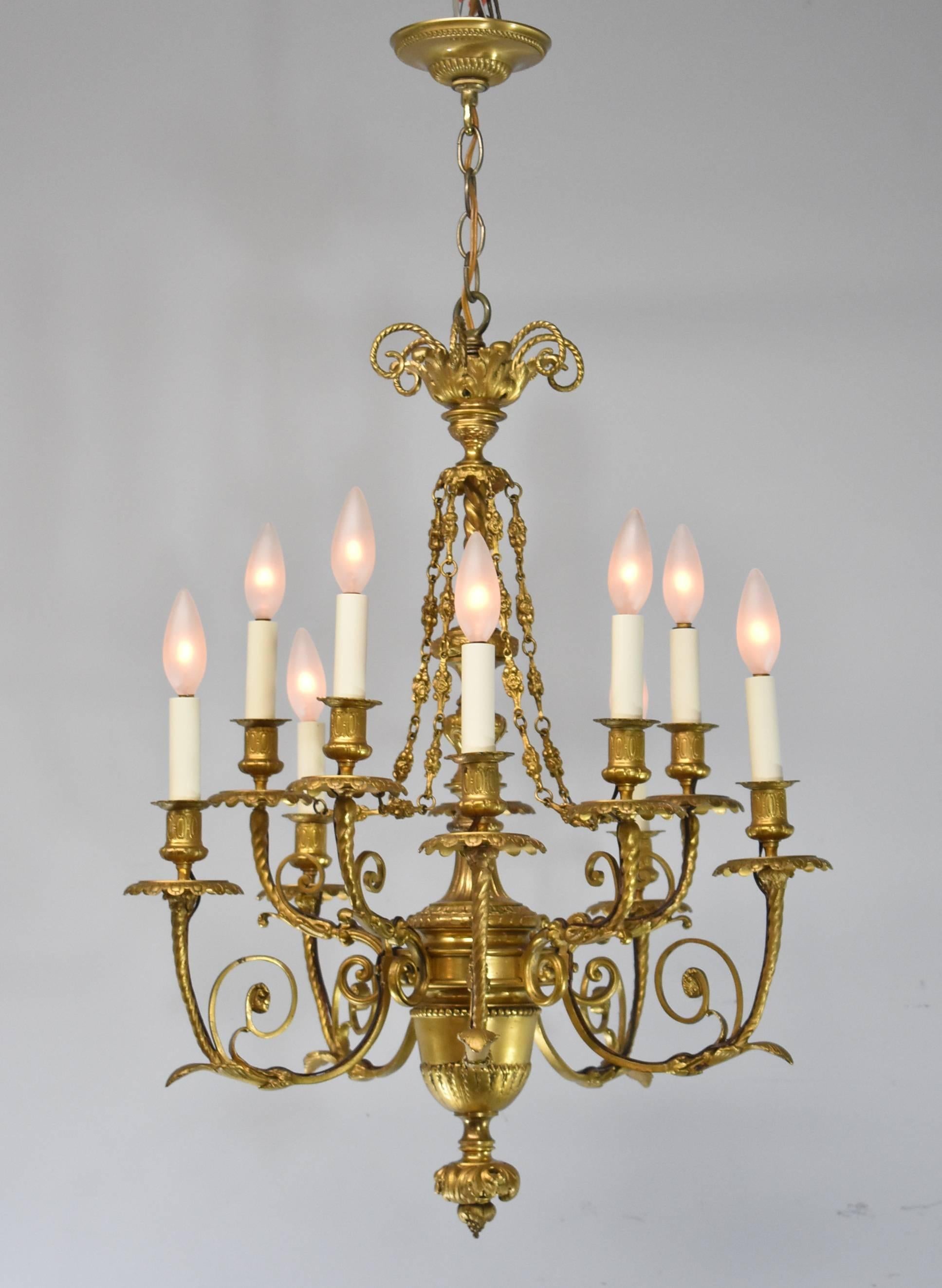 Beeindruckender zehnarmiger Kronleuchter im französischen Stil aus Bronze mit Gold-Doré-Finish. Verschnörkelter Swag und Rosendetails an der Kette. Die Lampenschirme sind nicht enthalten.