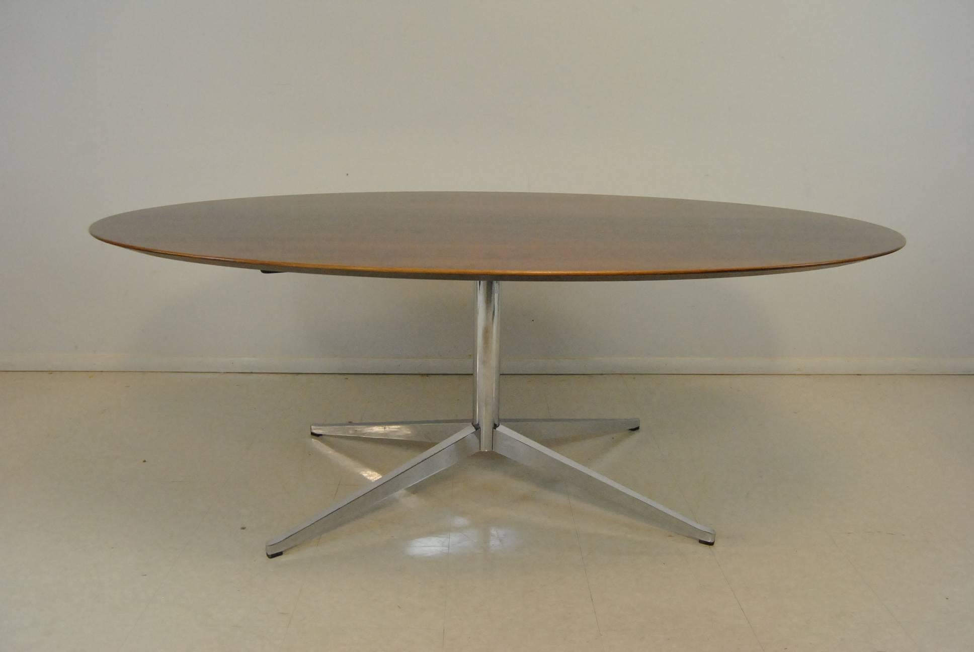 A fantastic conference or dining room table by Florence Knoll. This beautiful table features an oval Rosewood top with a bevelled edge and exceptional graining. It is supported by polished chromed four-star legs. The dimensions are 78
