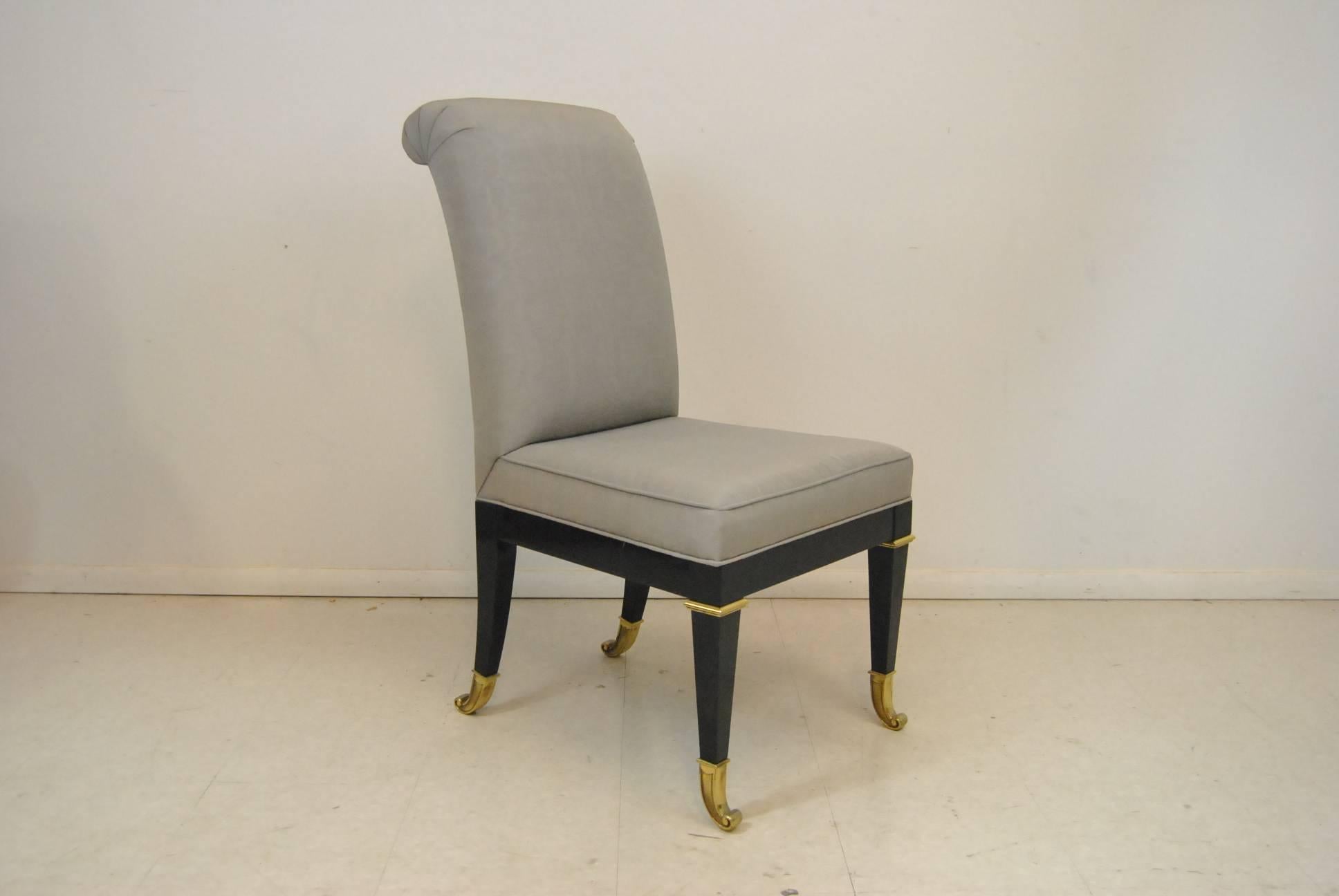 Ten Hollywood Regency style dining chairs in a Classic design from Mastercraft. Unusual brass feet and fittings. Sold as a set that includes eight side chairs and two armchairs - all with ebonized wood finish and brass feet. New upholstery is