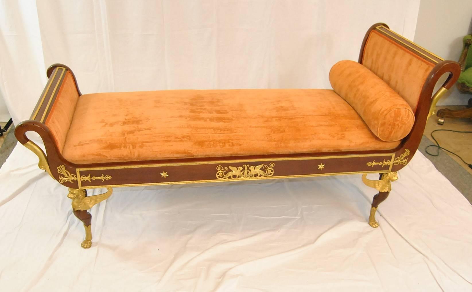A beautiful French Empire style recamier day bed.  The rich mahogany frame features outswept sides which end in bronze swan molded figures.  Legs have gilded bronze winged Lions and paw feet.  On the seat frame there are two winged griffins