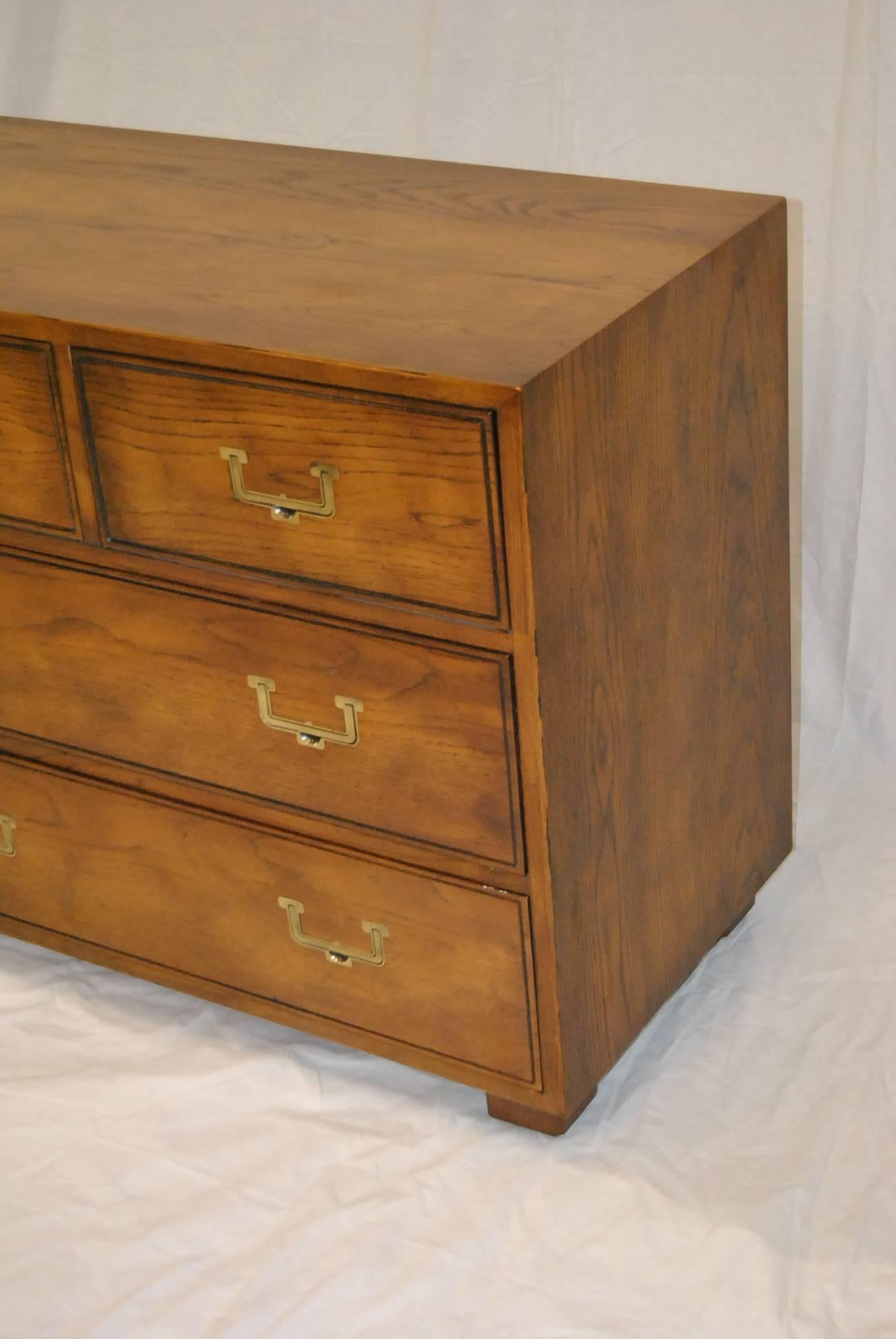 A beautiful oak campaign style dresser by Henredon as part of their Artefacts Collection.  It features 7 dovetailed drawers, original brass hardware, recessed handles and a divided center drawer.  Great constructuion and style.