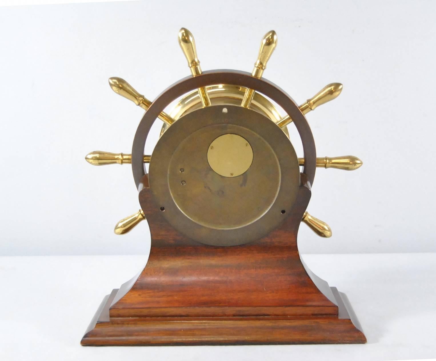 A classic Chelsea Ship's Bell Mantel Clock.  It features a mahogany stand, yellow brass case and spokes with an iconic brass ring.  4