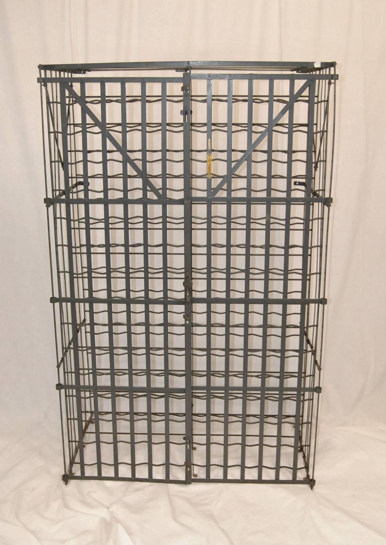 A commercial grade French strapped metal wine cage by Rigidex.  The wine cage can hold up to 300 bottles of wine in double rows.  Double doors have a locking hasp marked Rigidex (no Lock).  Yellow Rigidex tag adorns the front as does a tag stating