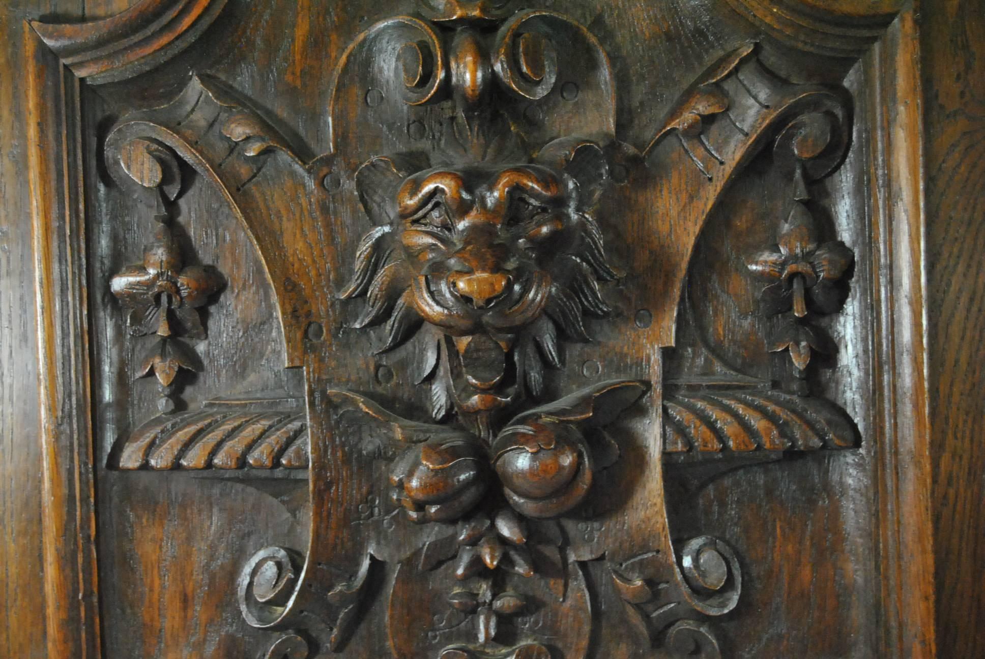 A stunning pair of Tudor style carved panels. These beautiful panels are finely hand-carved in solid oak. They feature a central lion head above a fruit cluster. High relief carvings that are 2 3/4