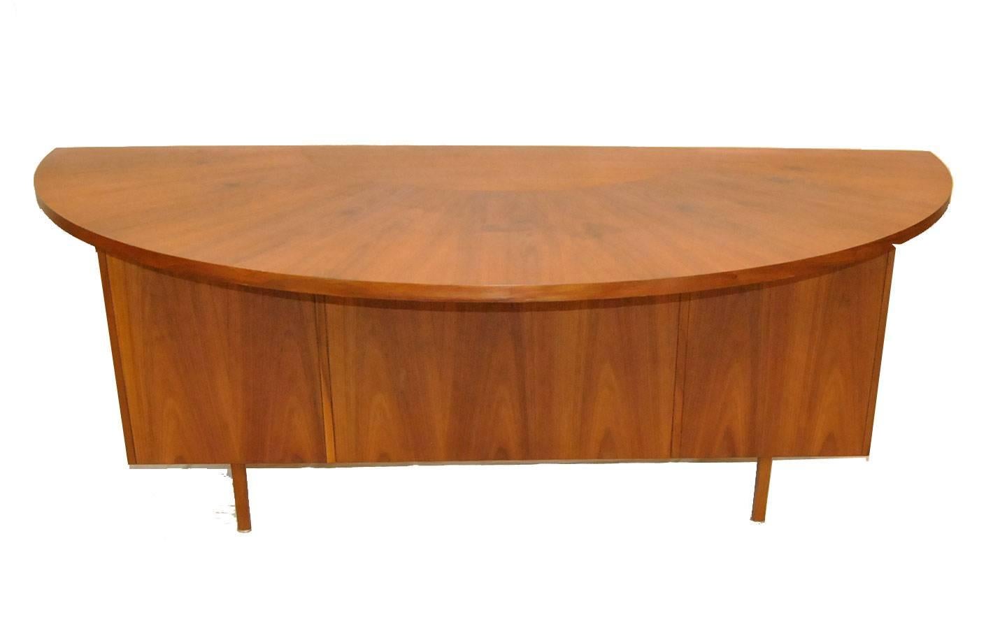 An unusual executive Desk with curved top made by Wood Design of French Lick, Indiana. The desk has a sunburst top and features two slide out shelfs, four side drawers, one center drawer and a file drawer. Hardware is a brushed metal.