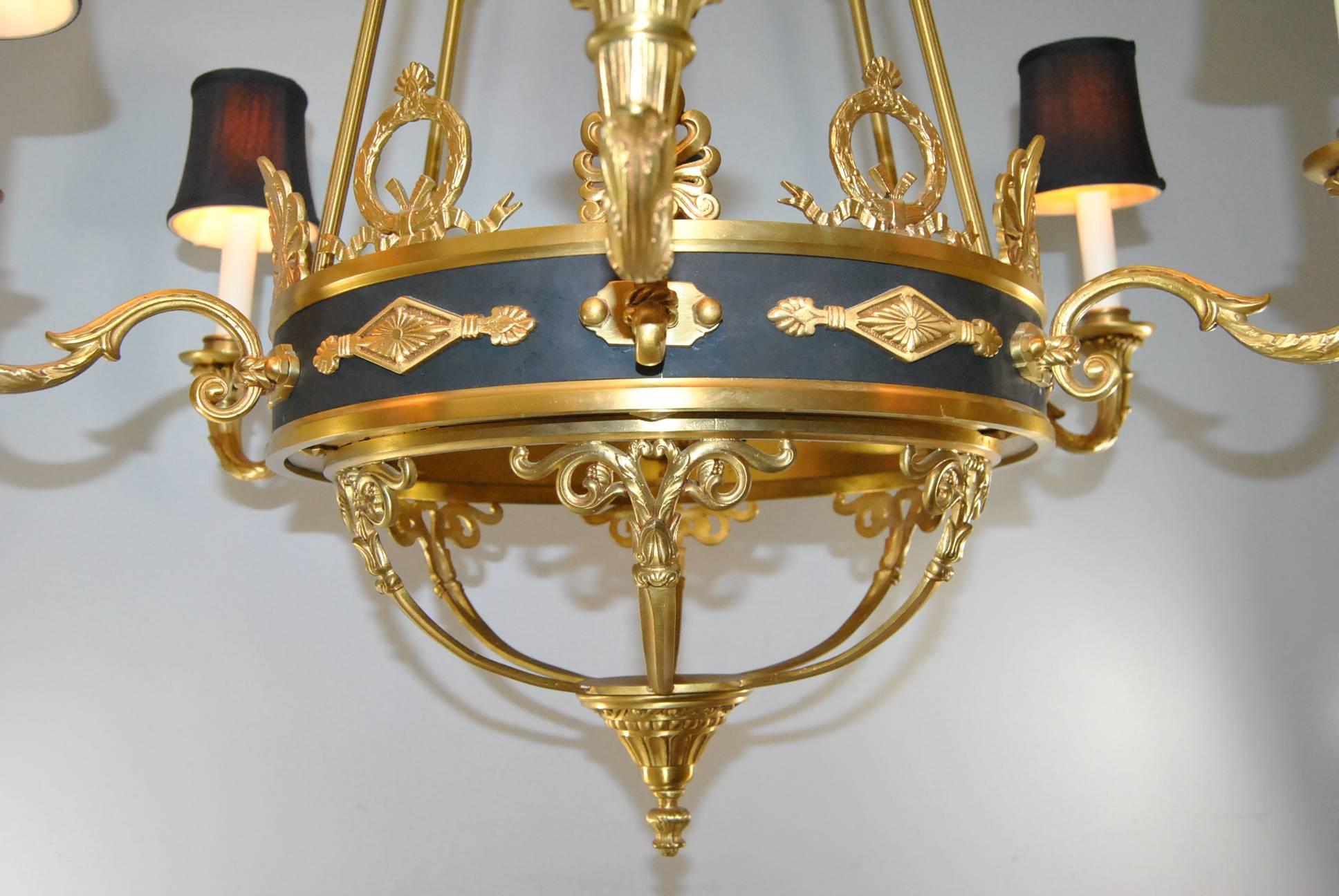 A beautiful French Empire style six-arm bronze chandelier with black tole accents. This chandelier has an open bird cage bottom with central finial. Great dore detail adorns the black body of the chandelier. The top crown is large acanthus leaf and