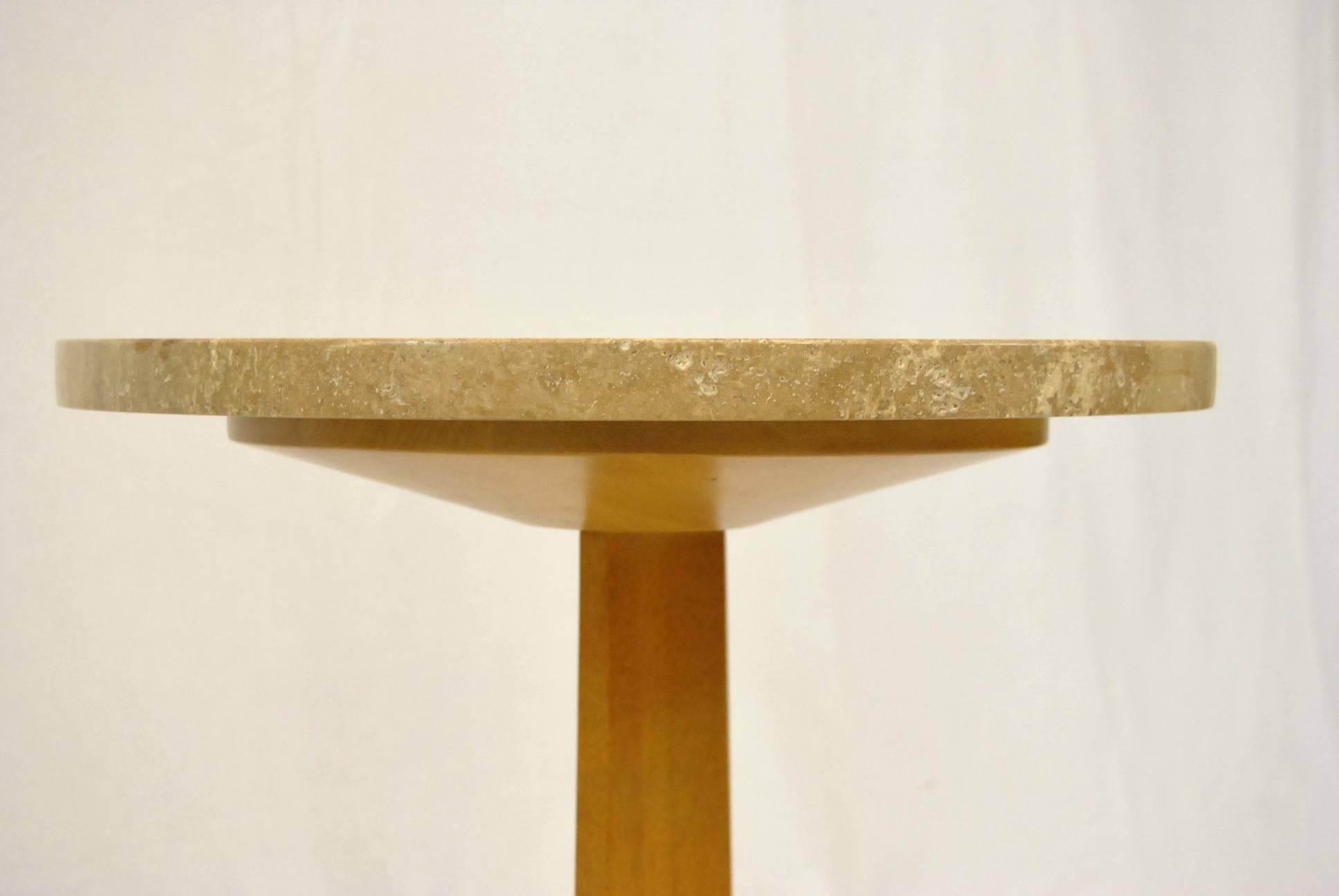 A great stand designed by Edward Wormley for Dunbar. Stand has a tripod base and is has a round travertine top. The Dunbar gold label is secured below the base. This is a great accent piece with multiple uses.