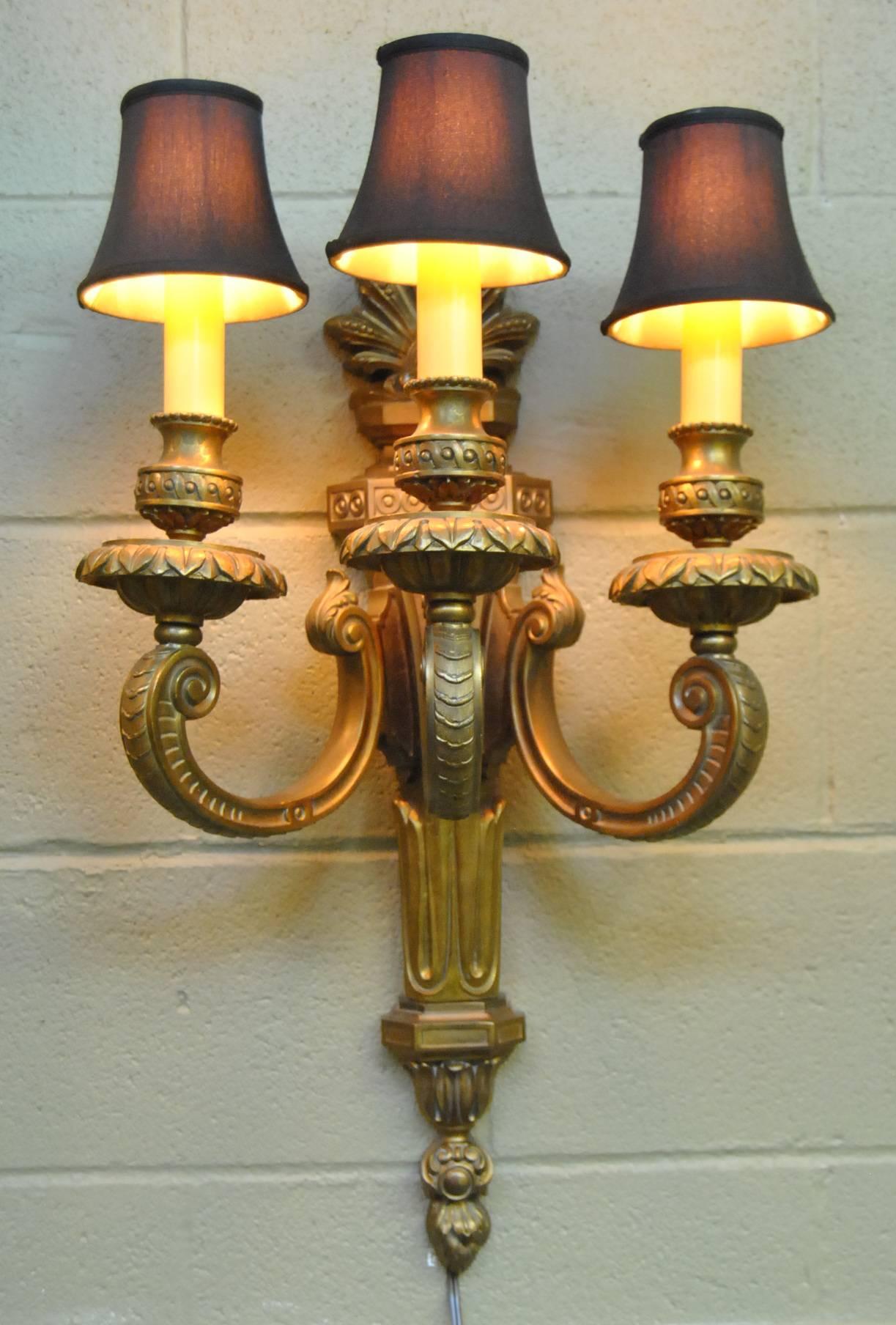 Stunning large-scale heavy cast bronze neoclassical three-arm wall sconce. Each candleholder has acanthus leaf details supported by scrolled arms. The bodies fluted form is accented by a plume design at the top. Fixture has been rewired. Measures: