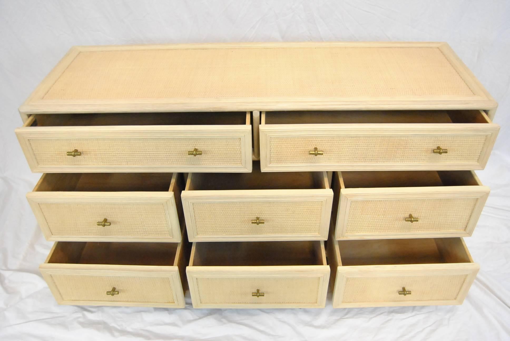 Ficks Reed long chest in cream whitewashed wood with caning panels on the eight drawer fronts, sides and top. Drawers have brass hardware, circa 1970s. Very nice pre owned condition.