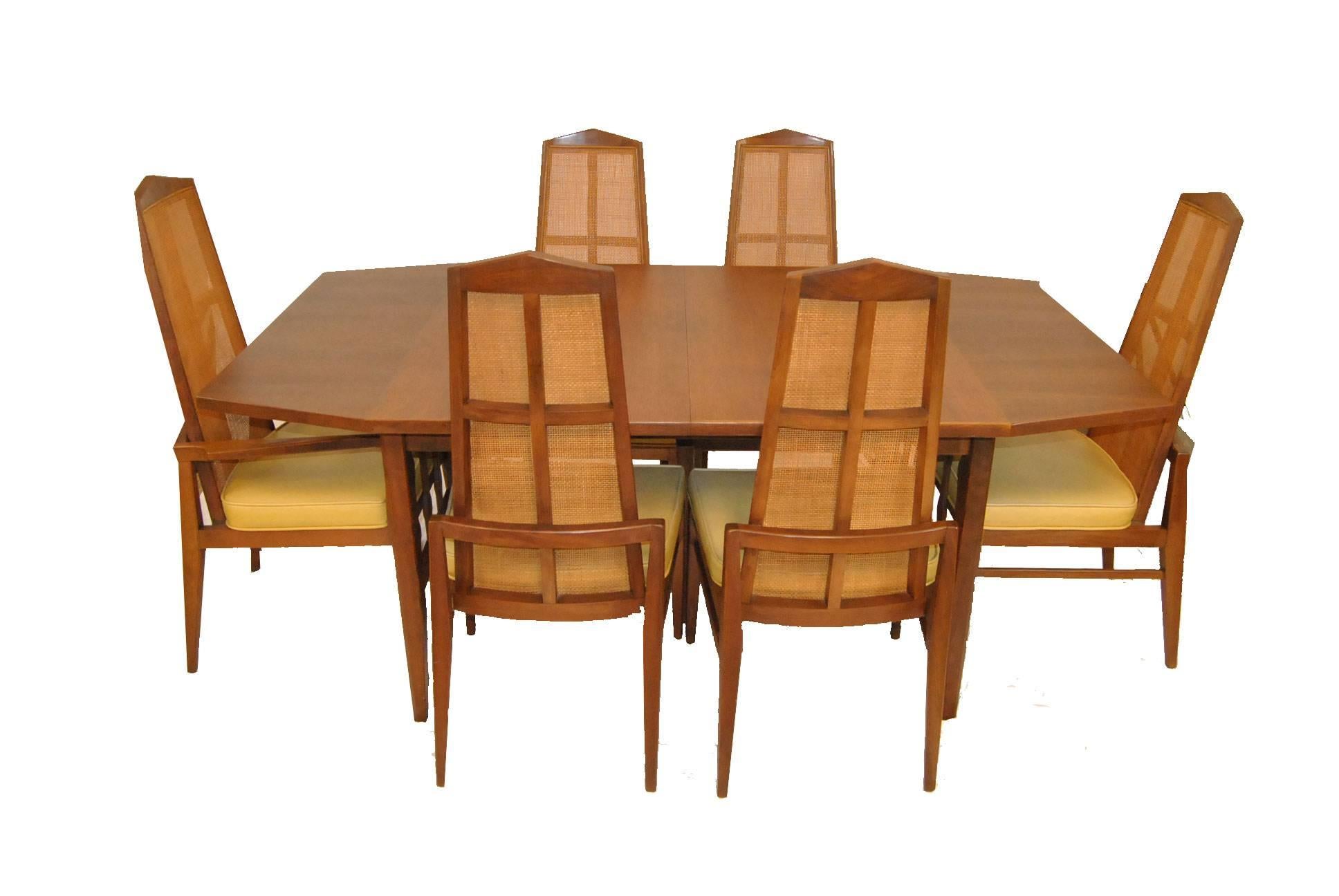 A beautiful set that includes the Probber style walnut octagon table and six chairs (one arm and five side chairs). Each chair features a tall caned back with crucifix frame and is upholstered in a pale yellow Naugahyde material. A great set from