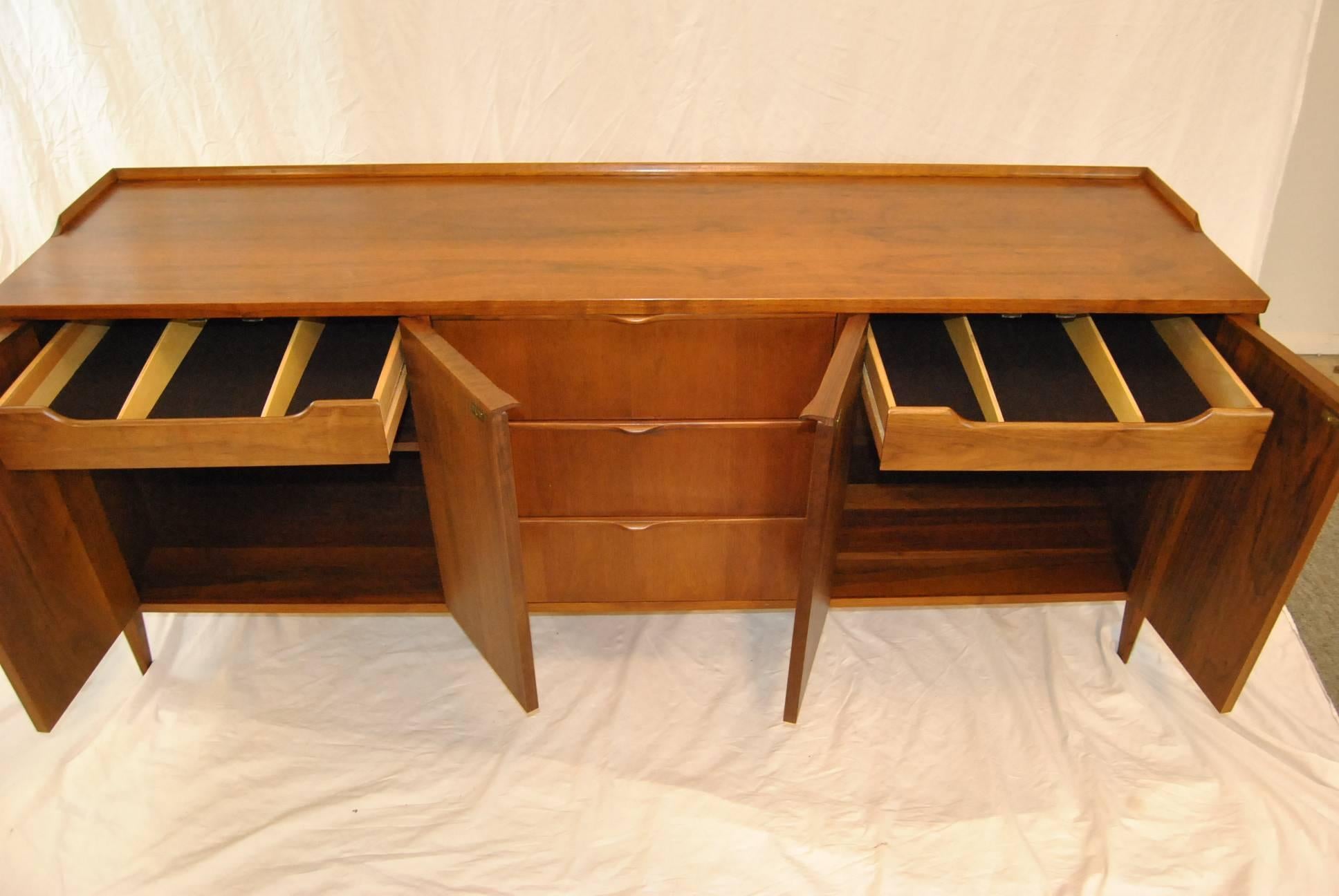 A beautiful Mid-Century Modern credenza by Foster-McDavid. Credenza features a right and left two-door storage area which bracket three dovetailed drawers. The walnut in this piece has beautiful graining which gives it a rosewood like appearance. In