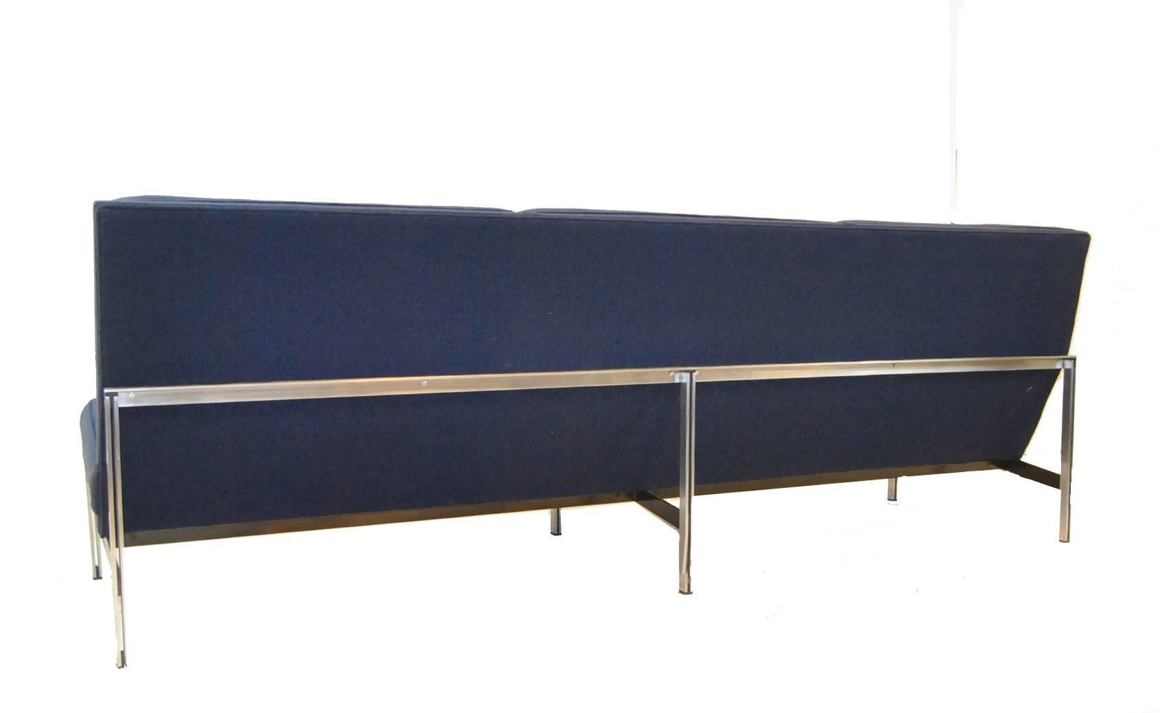 A Classic Mid-Century Modern Florence Knoll armless sofa. This is part of the Parallel series which features a chrome plated parallel base with black enamel supports. Sofa is upholstered in a blue cloth with tufted buttons on back and seat. Fabric