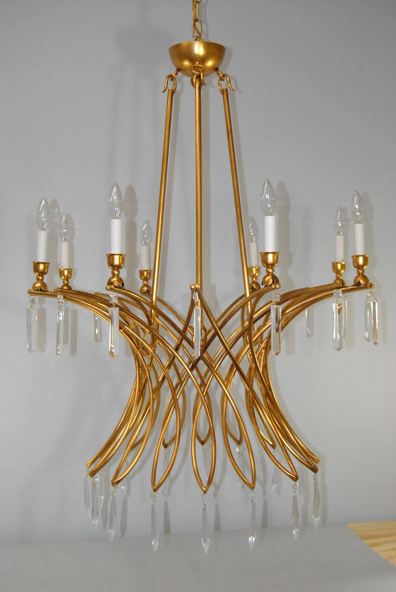 A dramatic large-scale Italian eight-arm chandelier in a gold finish. This large chandelier has eight arms in an intersecting elliptical pattern. Cut and polished prisms hang from the top and bottom of each arm. The arms are attached to the crown by